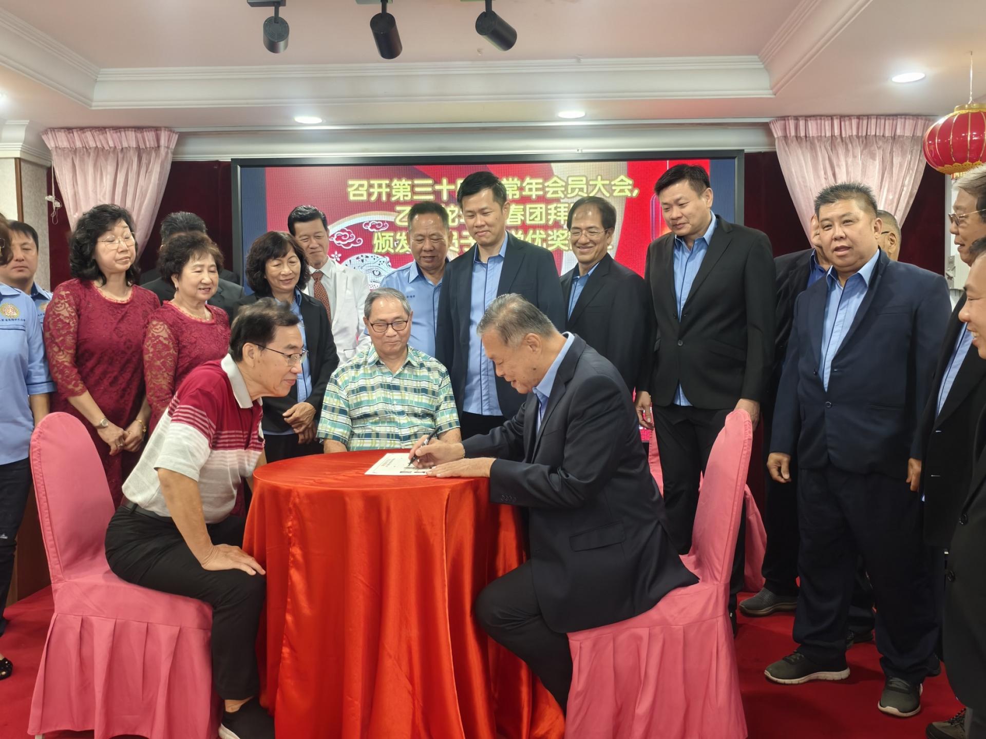 第16届主席许为隆（右）在宣誓书上签名。左起为监誓人名誉顾问许兆文及许美春。