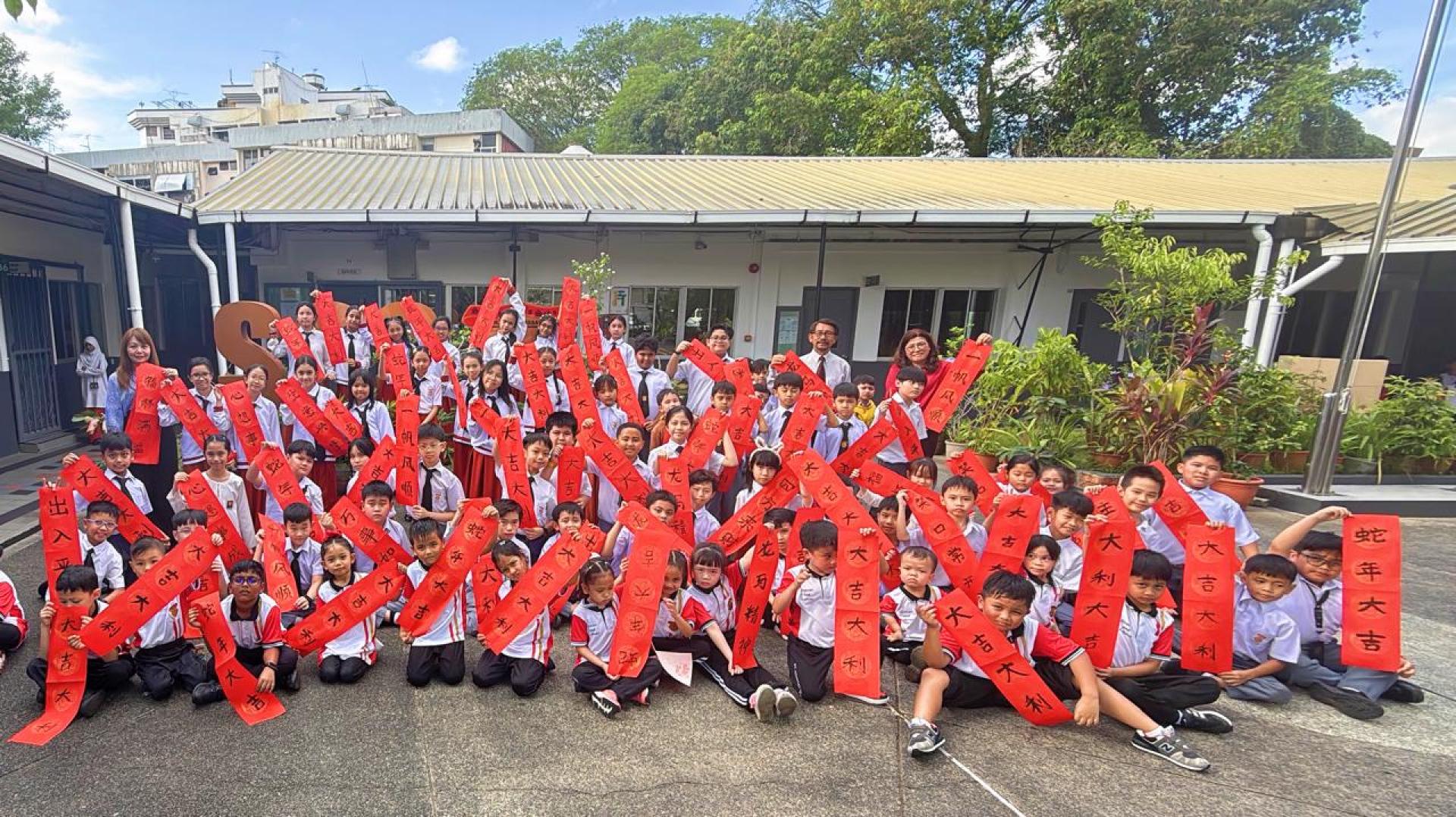 部分参加挥春大赛学生完成作品后与小学主任陈育赐（后右）及校长载倪迪（后右二）