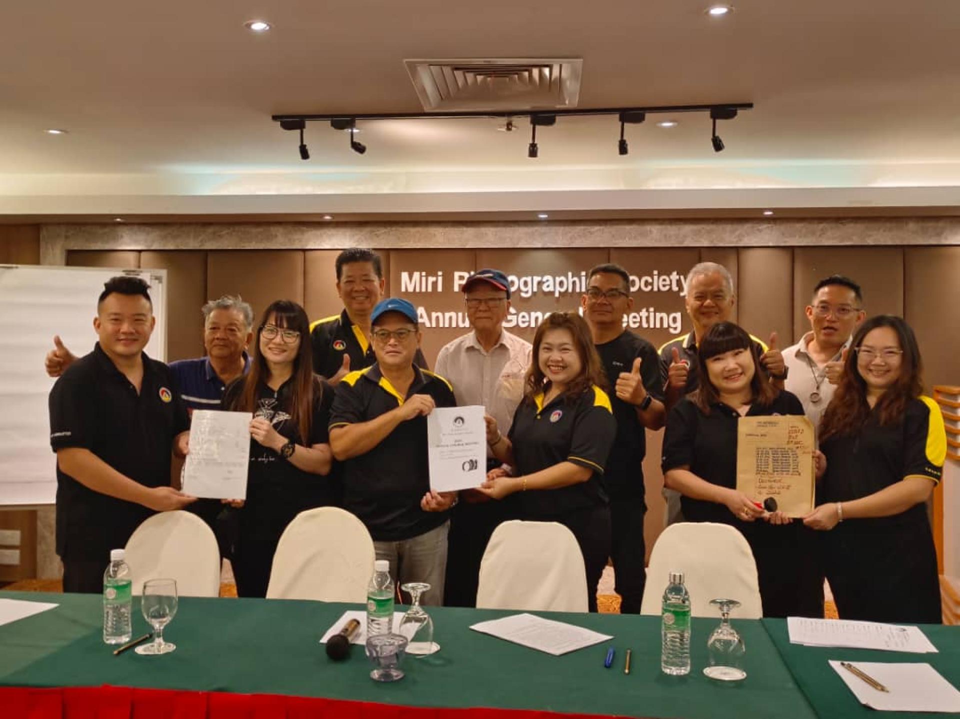 美里摄影学会会员大会暨改选后举行新旧领导层进行交接仪式。前排左起为卸任副财政邓志雄  移交职务给新任财政黄晓梅，卸任会长王维振将文件交接给新会长李佩佩，卸任秘书黄于沁移交文件给新任秘  书邓雪燕。由后排左起顾问刘庆宏，名誉会长萧特财，永久名誉会长陈乃豪，名誉会长周建平，名誉会长黄圣  勇，顾问洪立川见证。