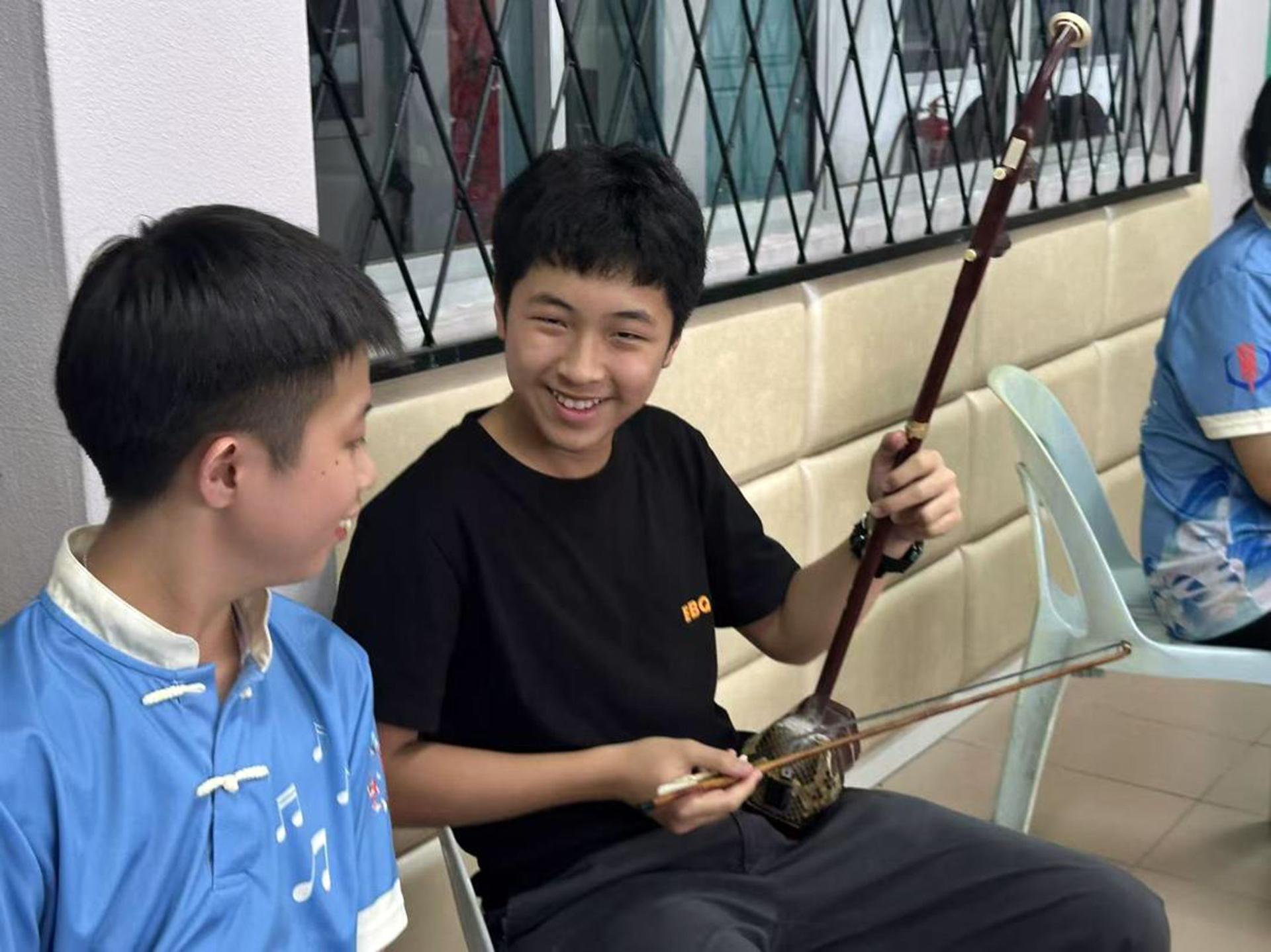 团员杨世杰（左）与新生热情交流，细心讲解二胡的演奏技巧，传递音乐的韵律与魅力。