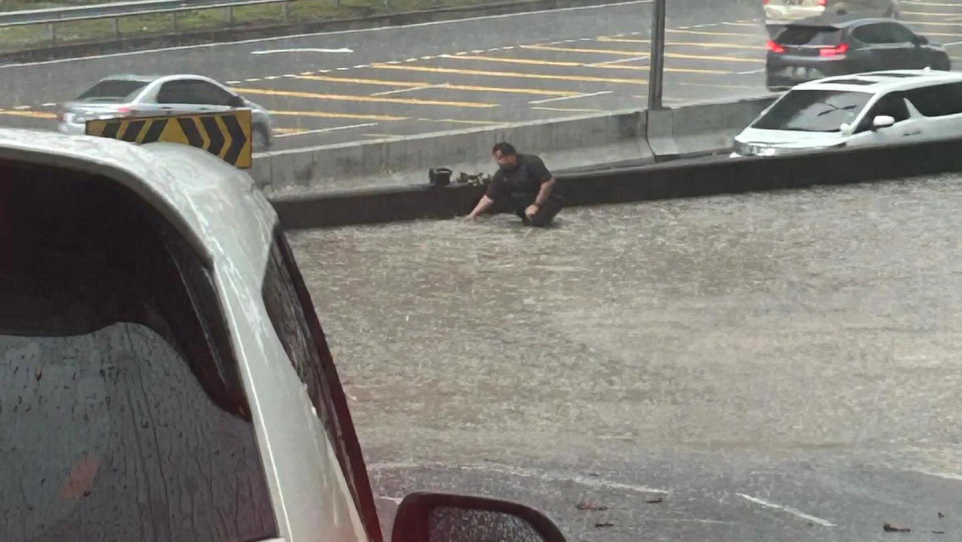 一名摩托车骑士冒雨走入积水中，赤手去清空排水沟的阻塞物，以让积水能够疏通，感动了无数人。