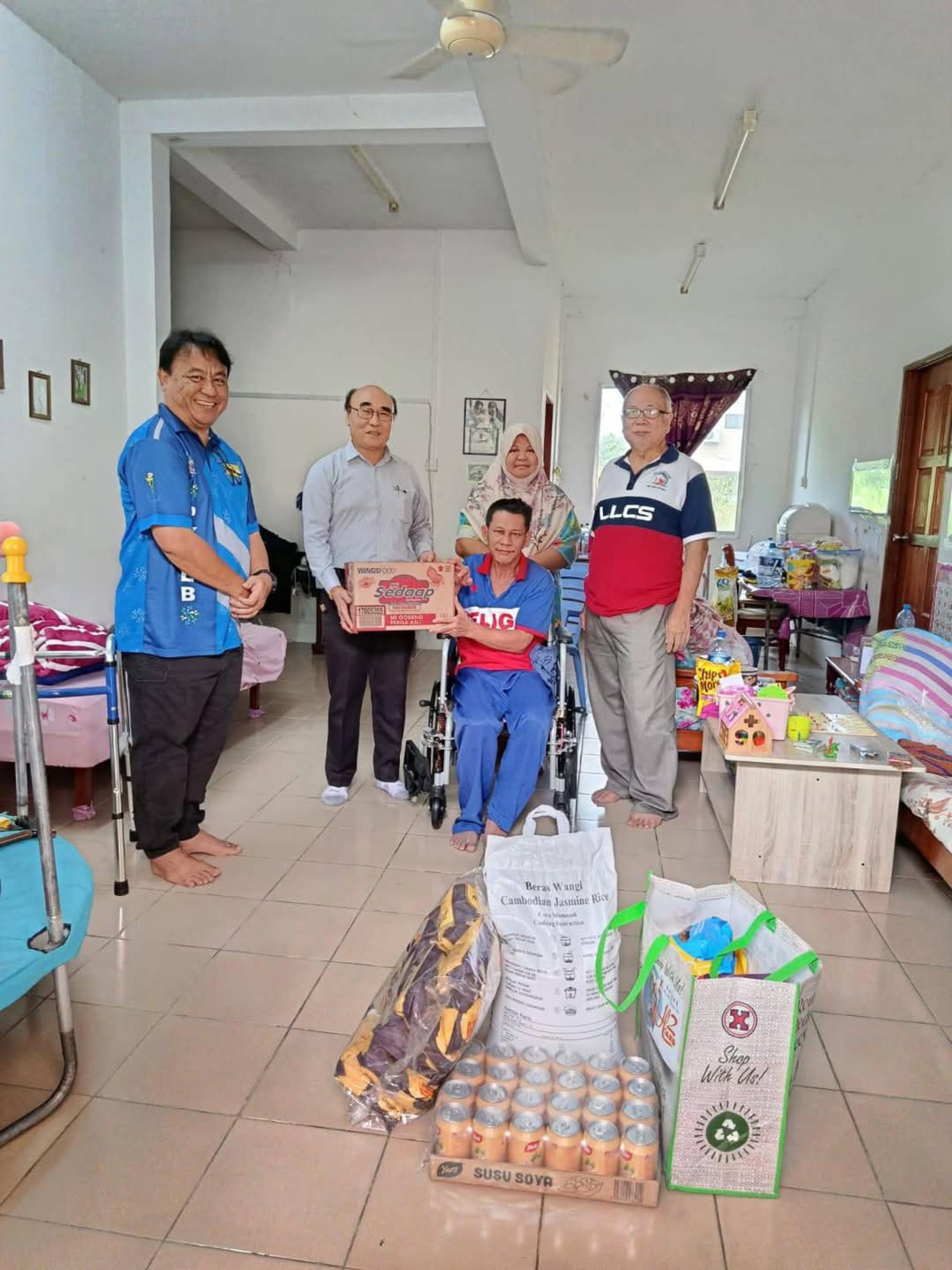 （左2）华光慈善会会长杨长乐，（右1）秘书长方永利与四轮驱动福利负责人阿比丁，共同分发斋月食品予其中一家贫困家庭