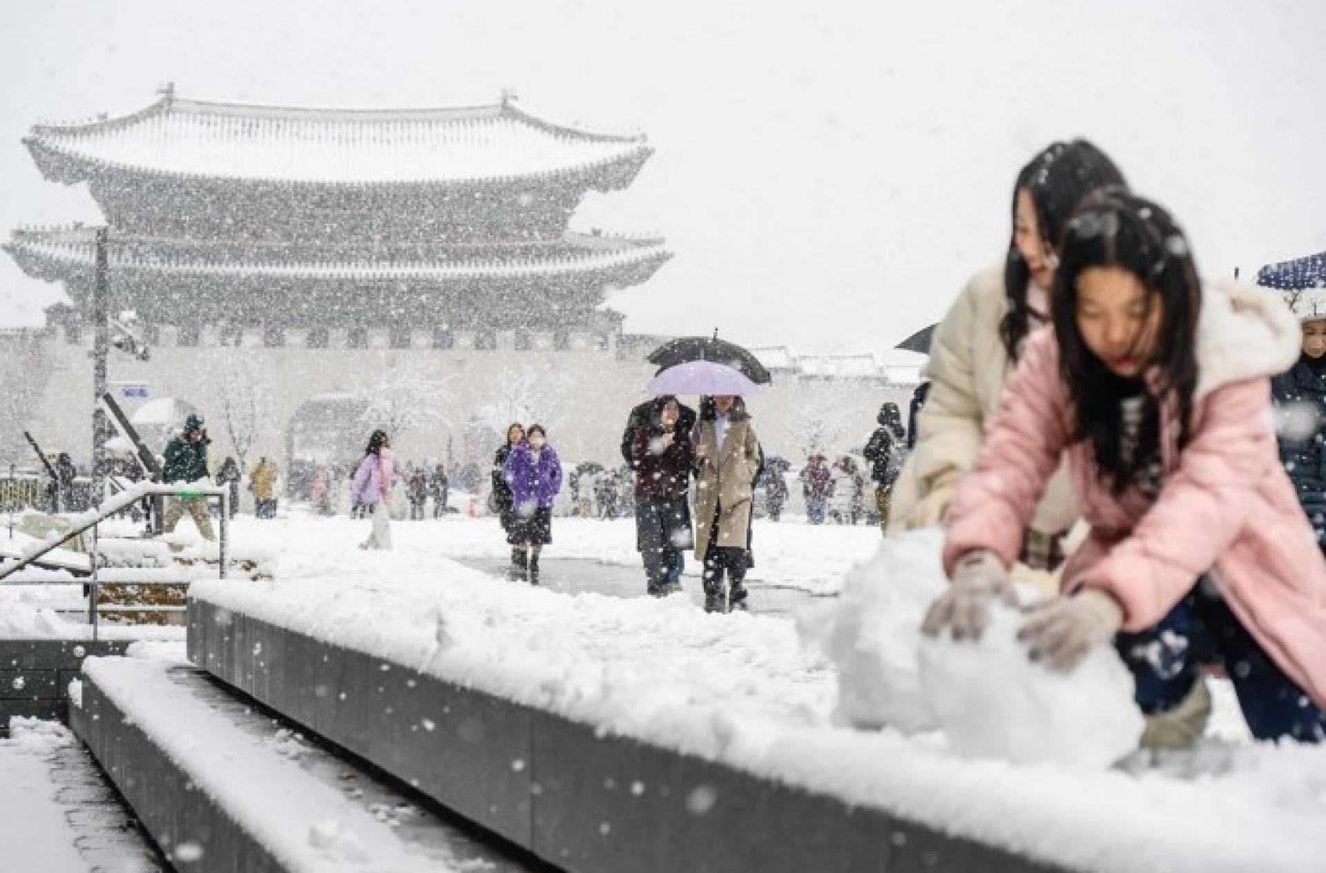 大雪纷飞，行人行走于首尔景福宫前。