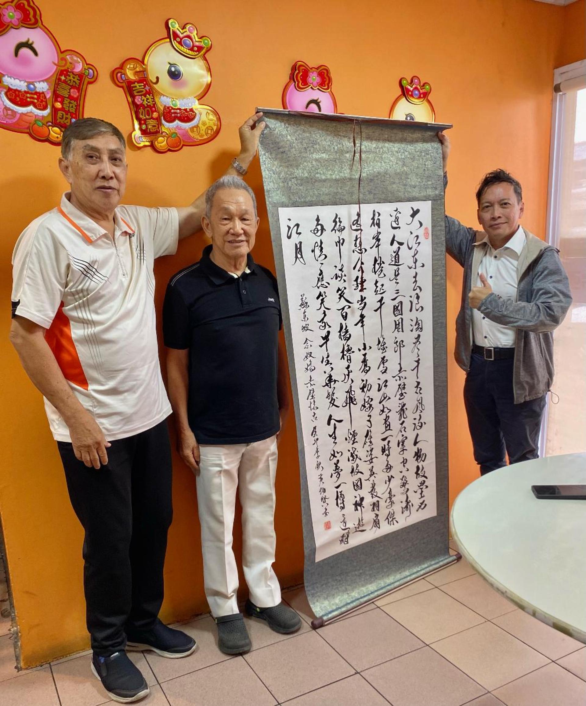 黄炳贤老师赠送书法作品予朱运利，中为世界华文作家协会会长暨汶莱中华文艺联合会的孙德安主席