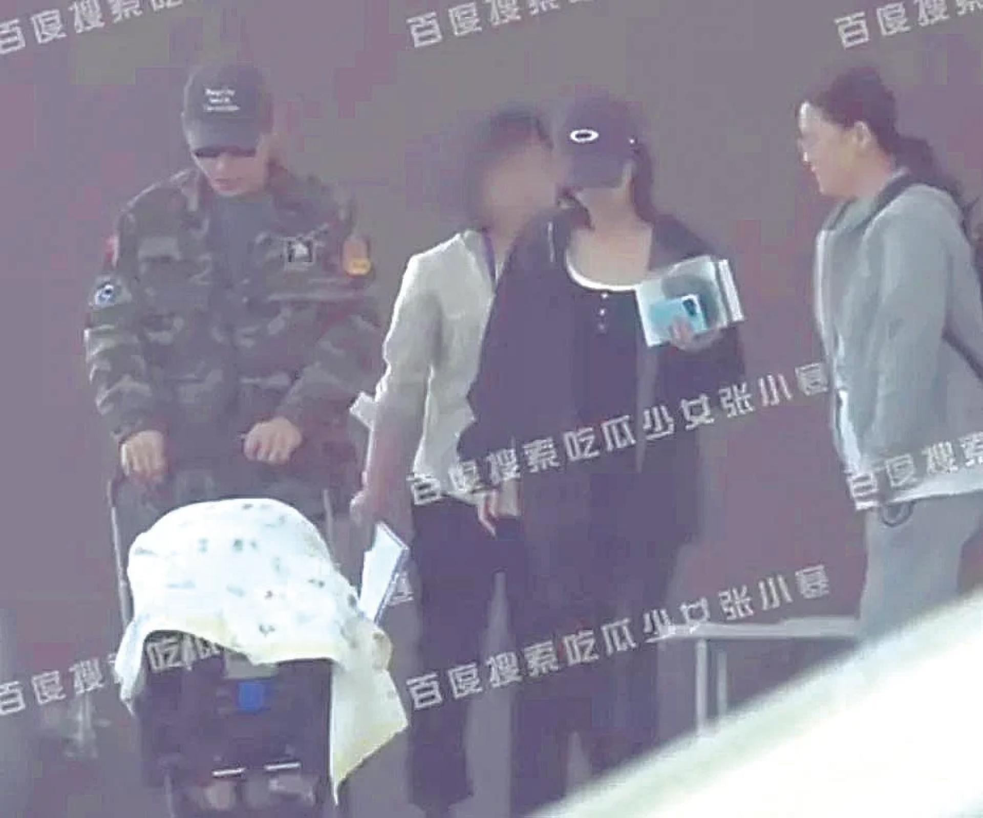 洪尧（左）推着婴儿车与老婆吴谨言（中）从医院走出来。