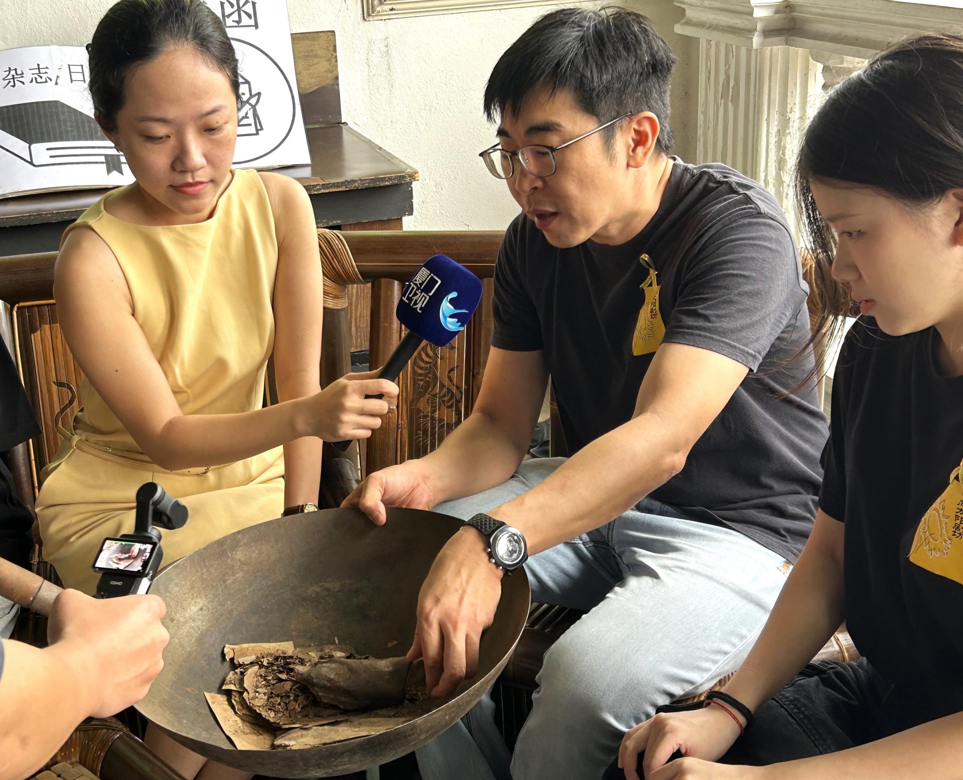 沈国明（中）向厦门卫视驻马记者吴晓燕（左）展示书籍保存不佳的情况，呼吁抢救史料，刻不容缓。旁是罗敏儿。
