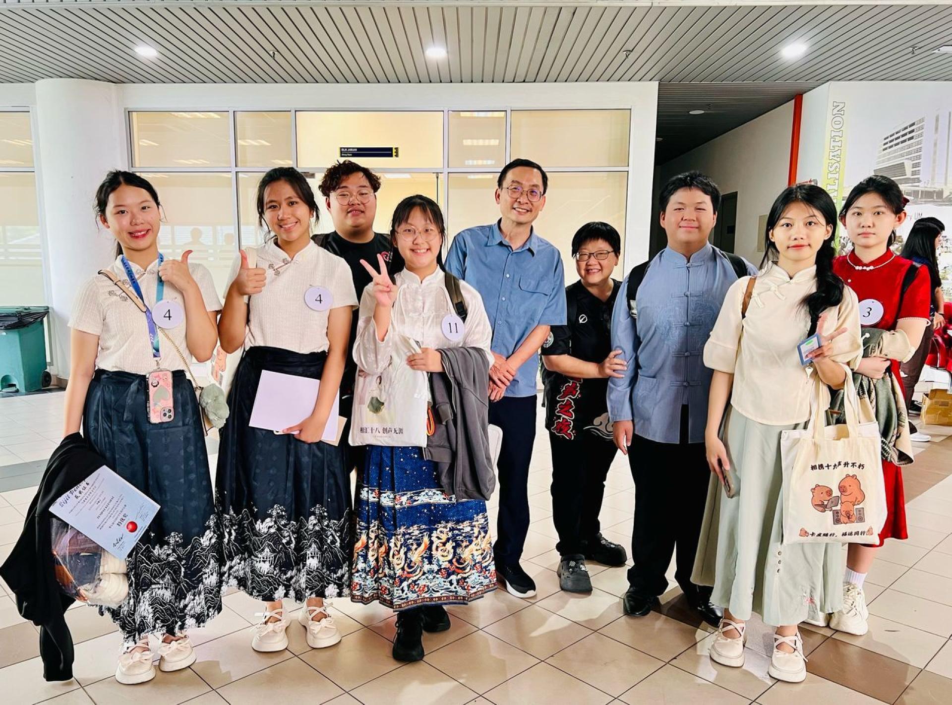 闯进全国决赛的队伍共12支，培中就占了4支，一时引起轰动，吸引了爱 FM DJ苏维胜（右5）访问培中带队老师陈逸萍（右4）。