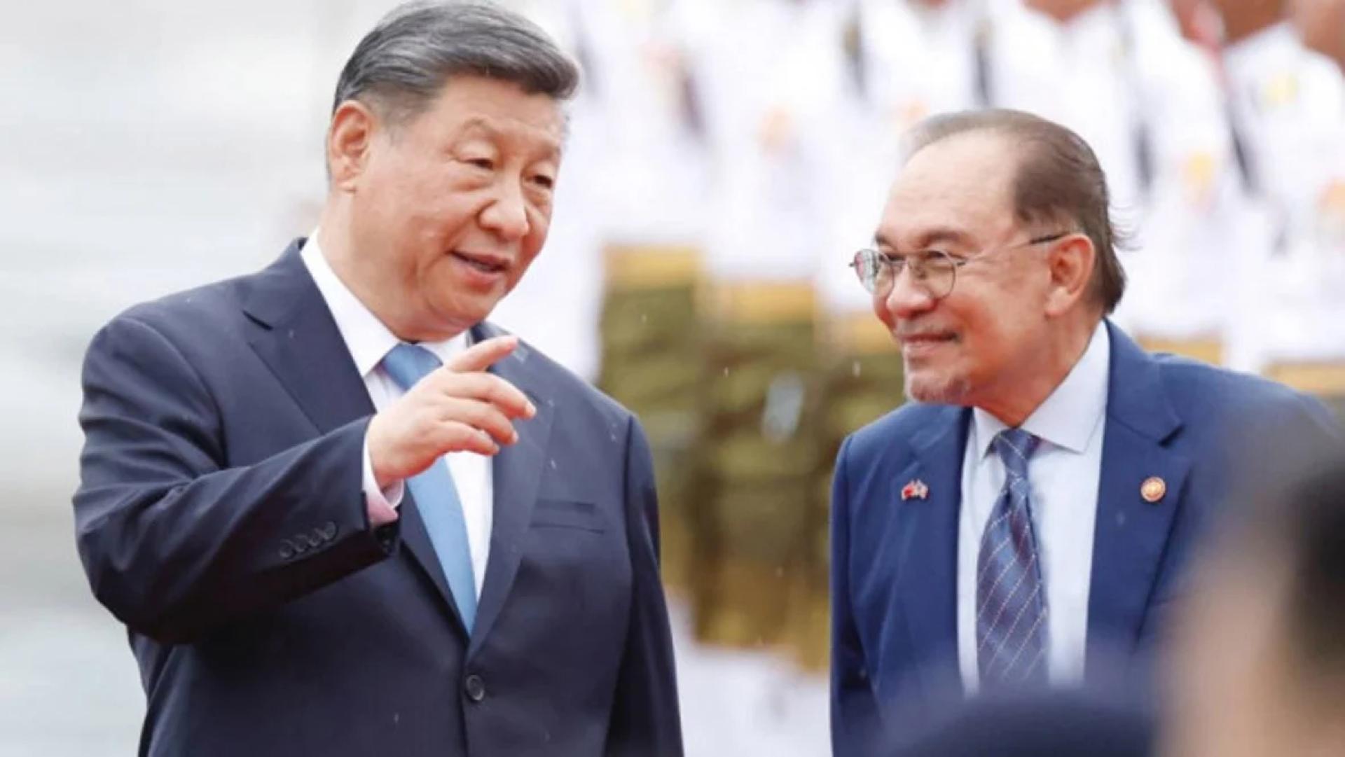中国国家主席习近平（左）乘专机抵达吉隆坡，在马来西亚进行国事访问，右为大马首相安华。（图：中新社）