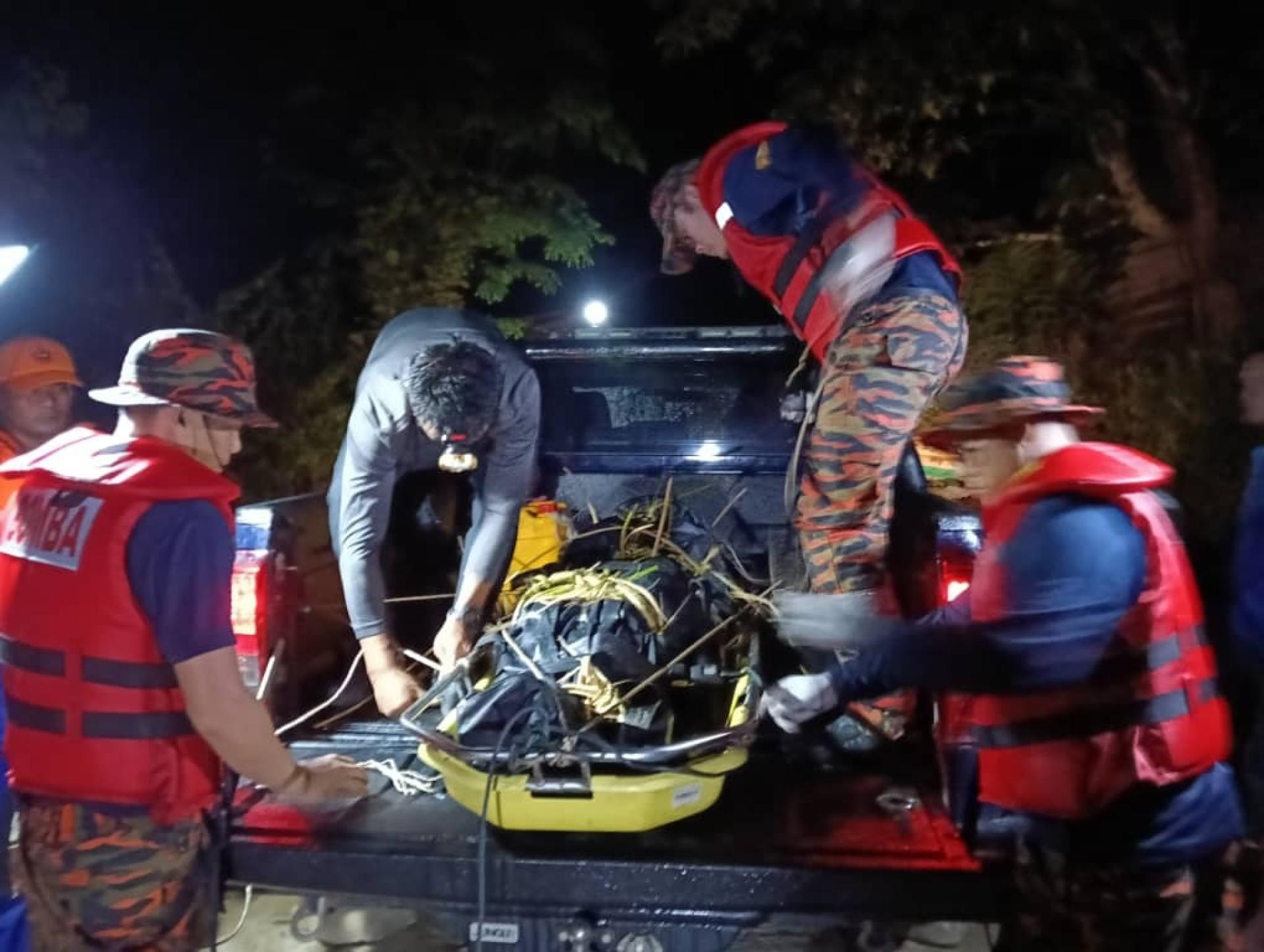 消防人员将死者遗体移上汽车。