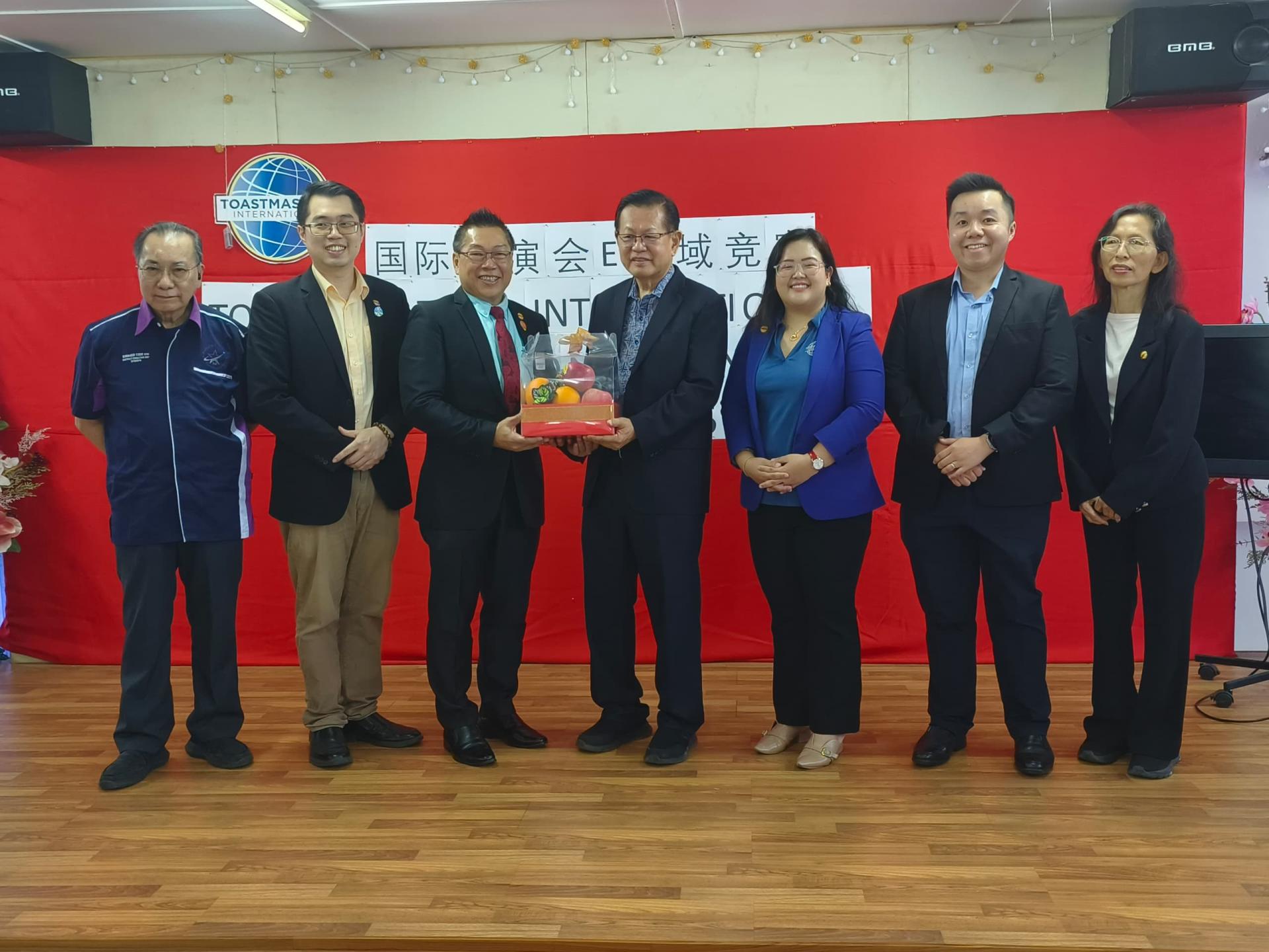国际演讲协会E区域总监刘会鹏(左三)赠送水果礼篮予李景胜。