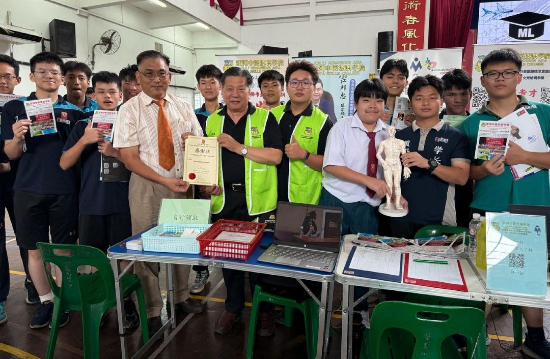 砂医总会长江宗兴（前排左4）由黄中学校长卢友雄手中  接过参与黄中的教育展感谢状。