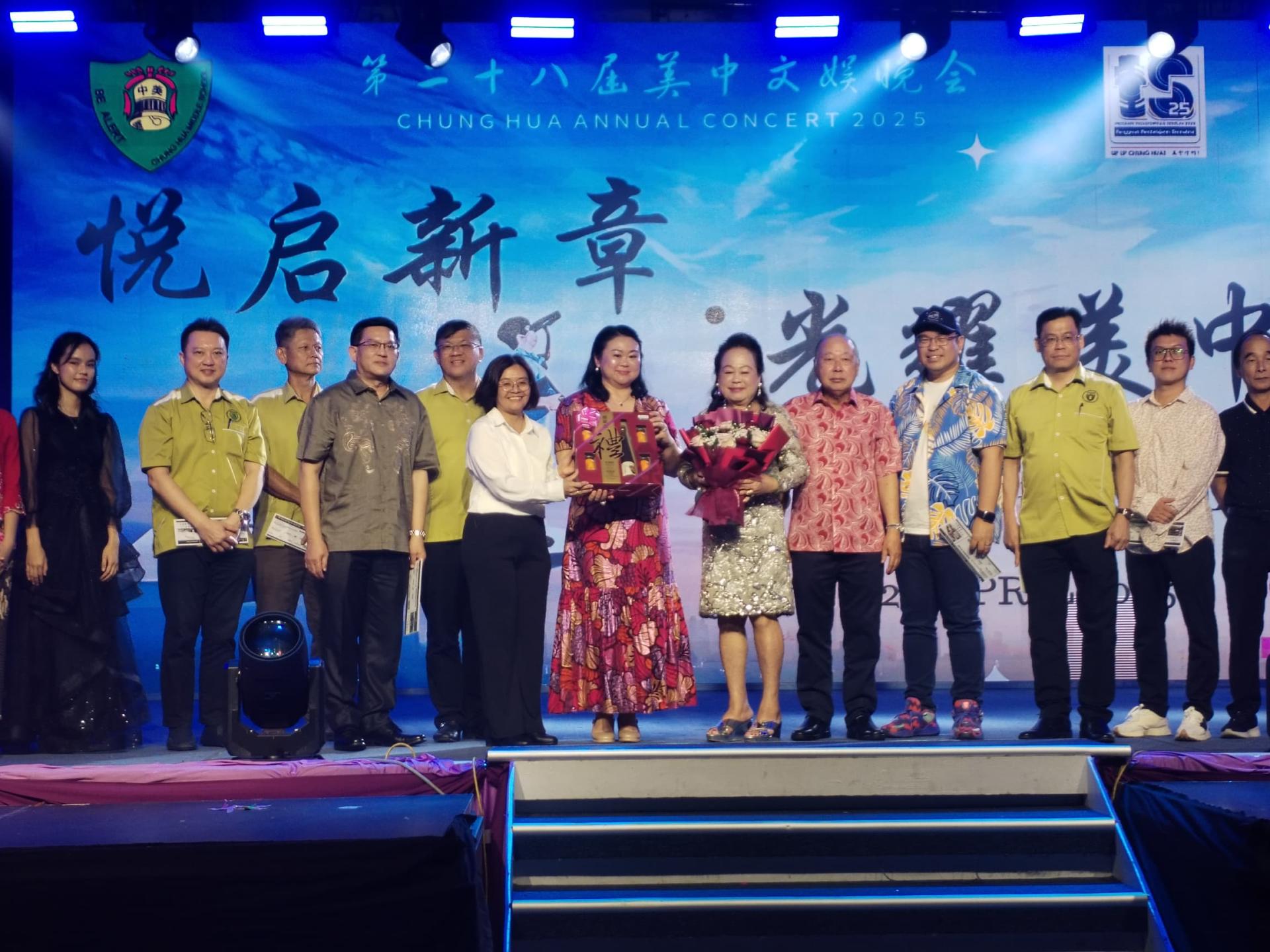 美中校长赖佳玲(左6)及董事部秘书陈丽黛(左7)在美中2025年“悦启新章，光照美中”文娱晚会上,赠  送纪念给董事长丹斯里拿督巴杜卡蔡幼兰(右6)合影。