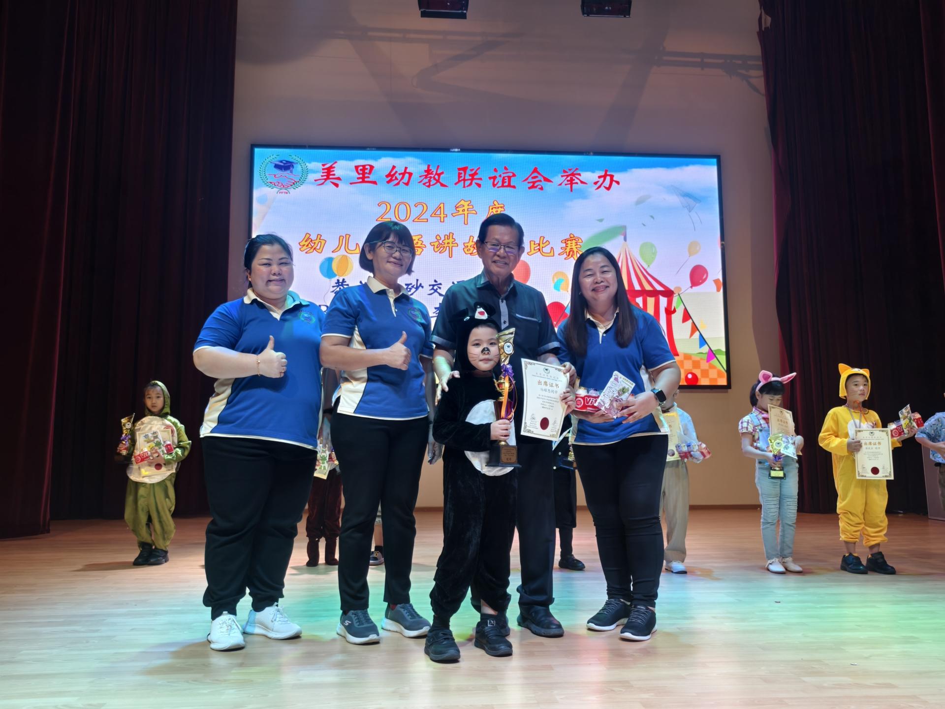 2024年度幼儿华语讲故事比赛冠军得主冯耀恩从闭幕主宾砂交通部长拿督斯里李景胜（左3）手中接过奖品。左起为美里幼教联谊会副主席吴妙云园长、筹备会主席蔡瑞华，以及主席沈秀芳园长（右）。
