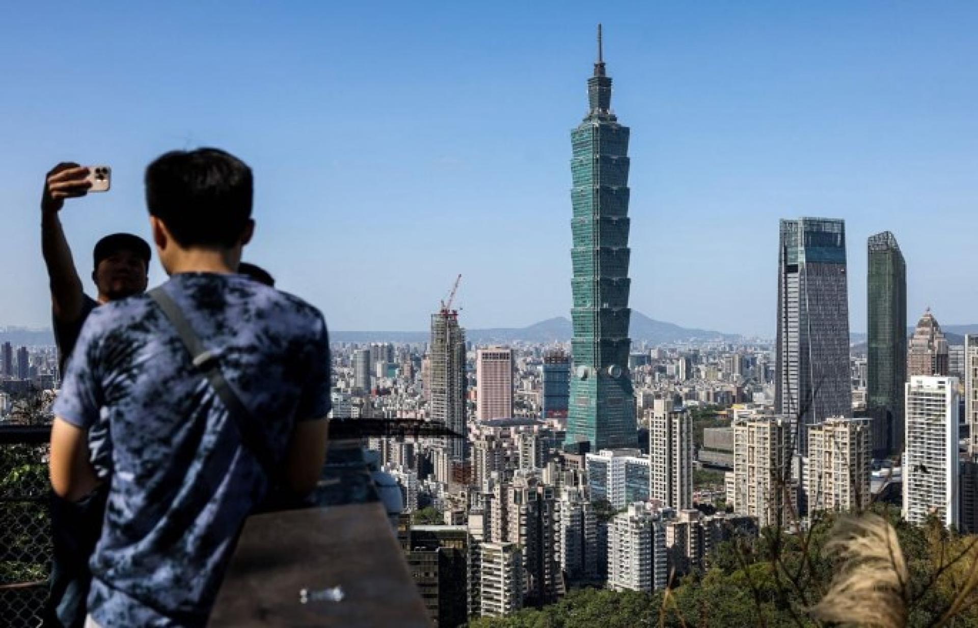 两岸观光开放议题，陆委会、国台办持续口水战。图为游客在台北象山拍摄照片。