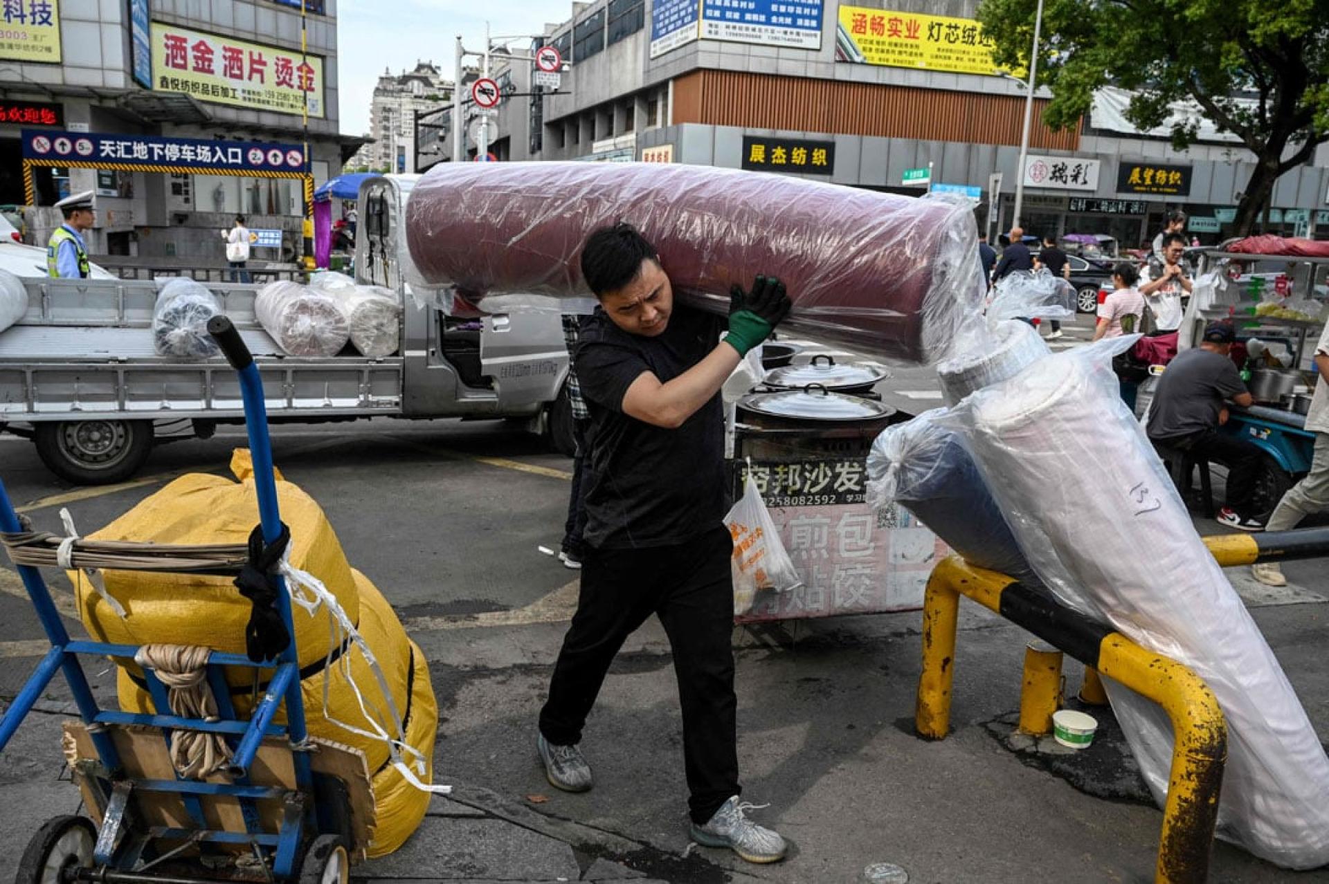 中国浙江省绍兴市，一名男子在纺织品市场外运送布料。
