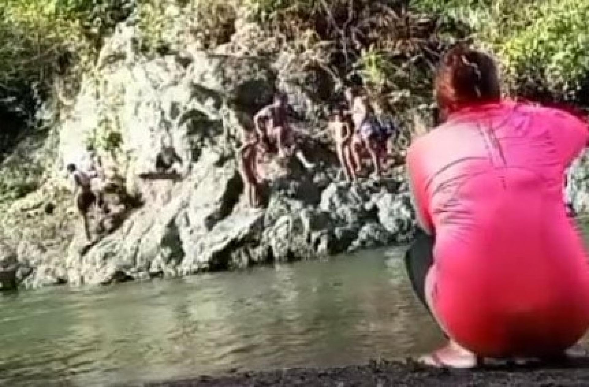 母亲正在为准备跳水的家人拍照。