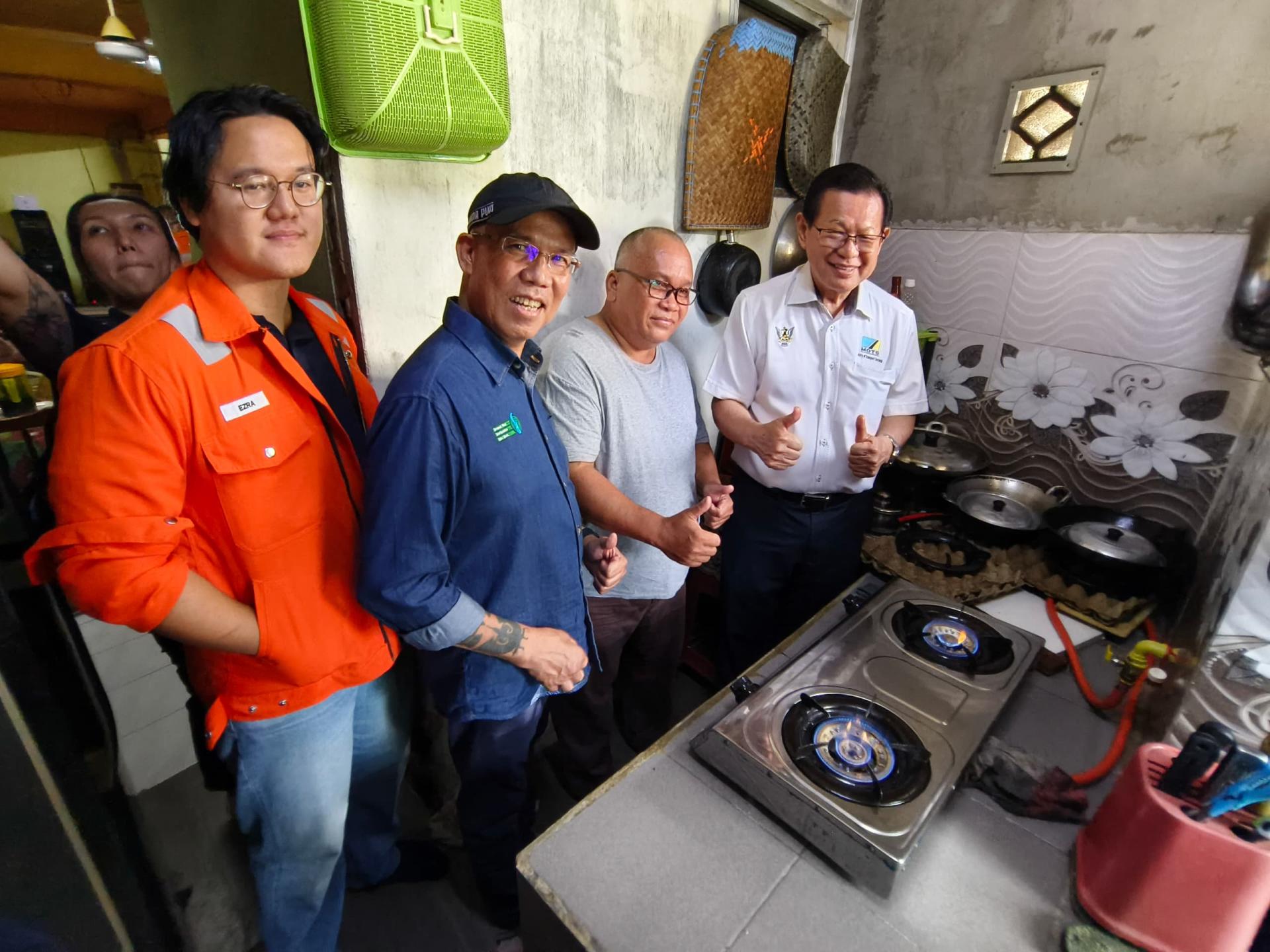居民在达雅佳节前顺利获得天然气供应，并开炉与到访的拿督斯里李景胜（右）分享。