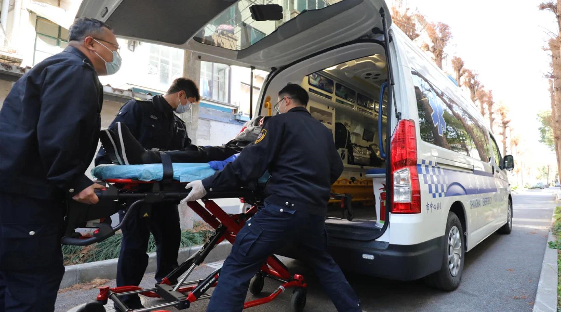 上海市医疗急救中心的工作人员将患者推上救护车。