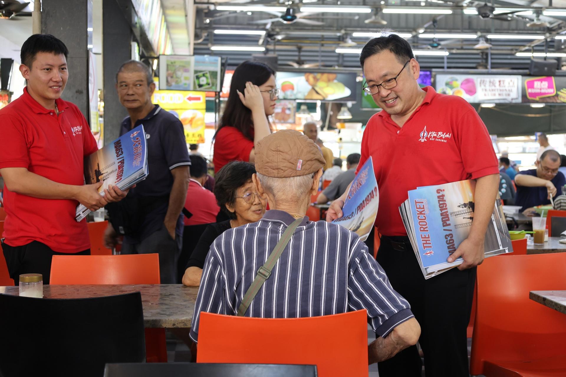趁着州议会周末休会，砂民主行动党主席兼浮罗岸区州议员暨实旦宾区国会议员张健仁（右1）昨日与其团队成员，在达万再也一带商店区推销《火箭报》。左1为张健仁特别助理沈杰龙。