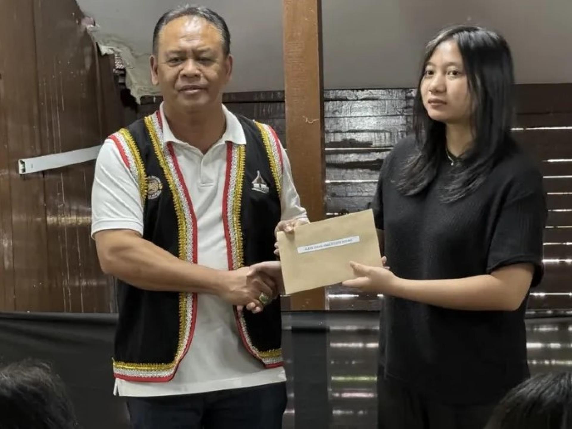 亨利将教育奖励金交给一名受益者。