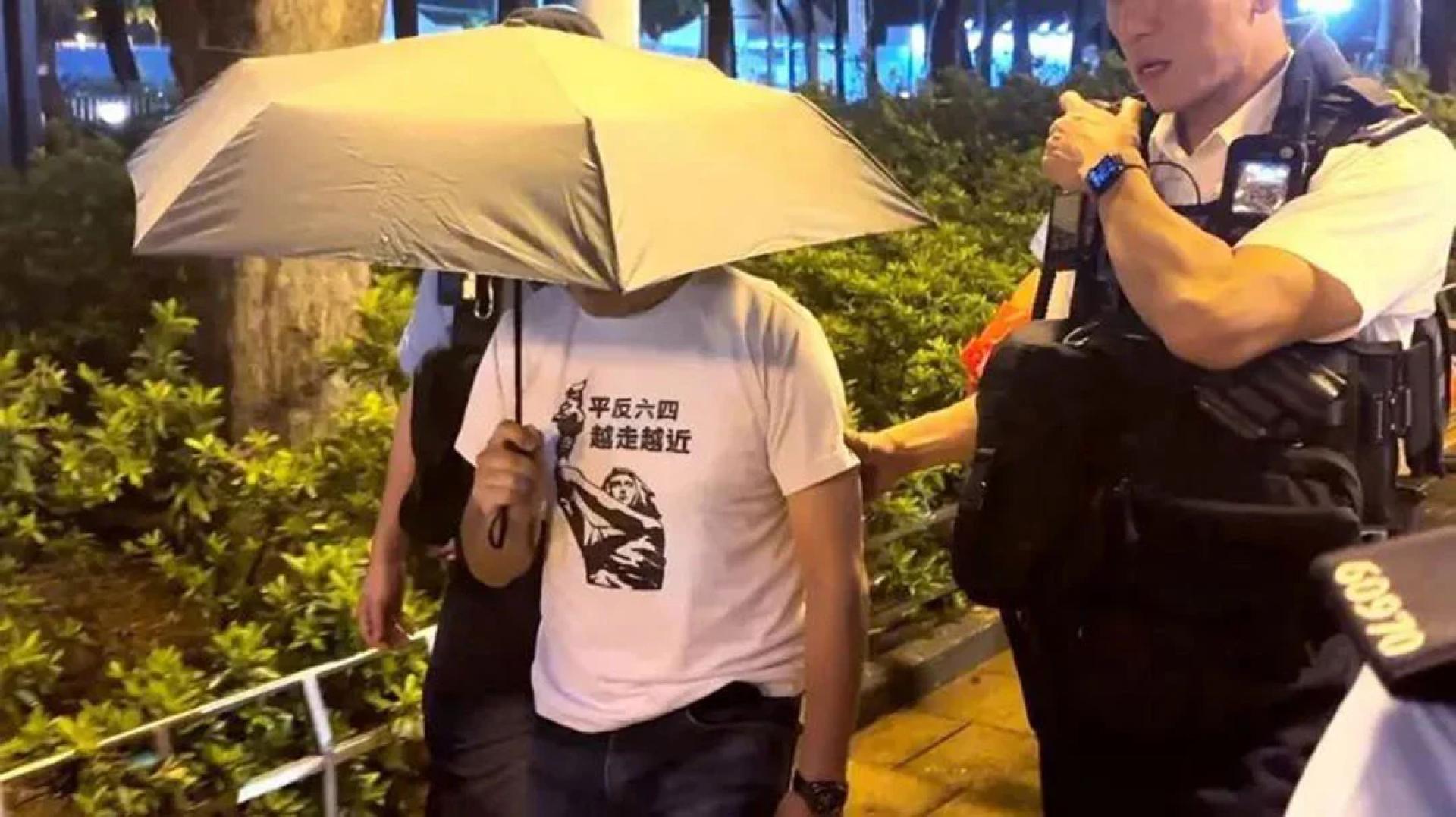 一名身穿“平反六四 越走越近”字样及“民主女神”图像上衣的男子4日在维园被警方带上警车离开。