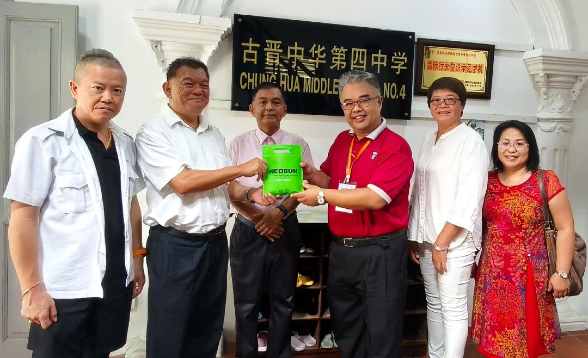 陈中兴医师（左2起）将四中义卖的药贴，在会诊顾问刘祐宏见证下移交给官晨阳校长。右起为助理符燕妮、叶美伺医师及田靖荣医师（左）。