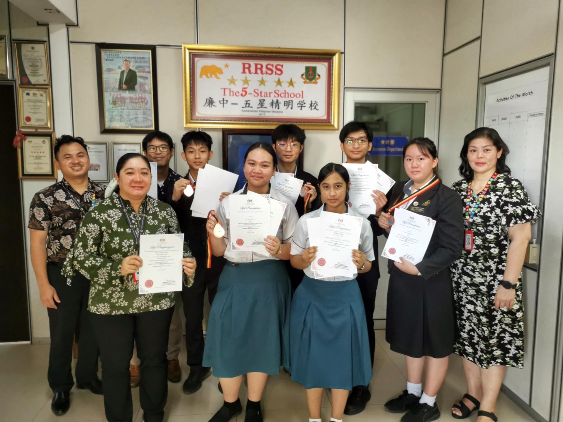 校长江佩娟（前排右一）、副校长康亚雄（后排左一）与荣获佳绩的 英文辩论队伍及带队老师艾美丽（前排左一）、范其远（后排左二）合影留念，以表 彰师生的辛勤付出与卓越表现。