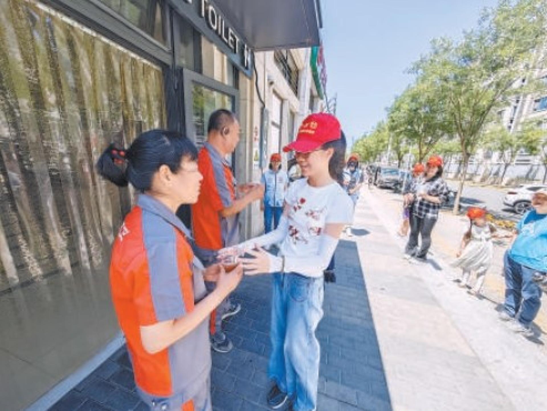 上周末，石景山区古城街道建兴街社区工作人员和志愿者将冰镇好的绿豆汤送到户外工作者手中。