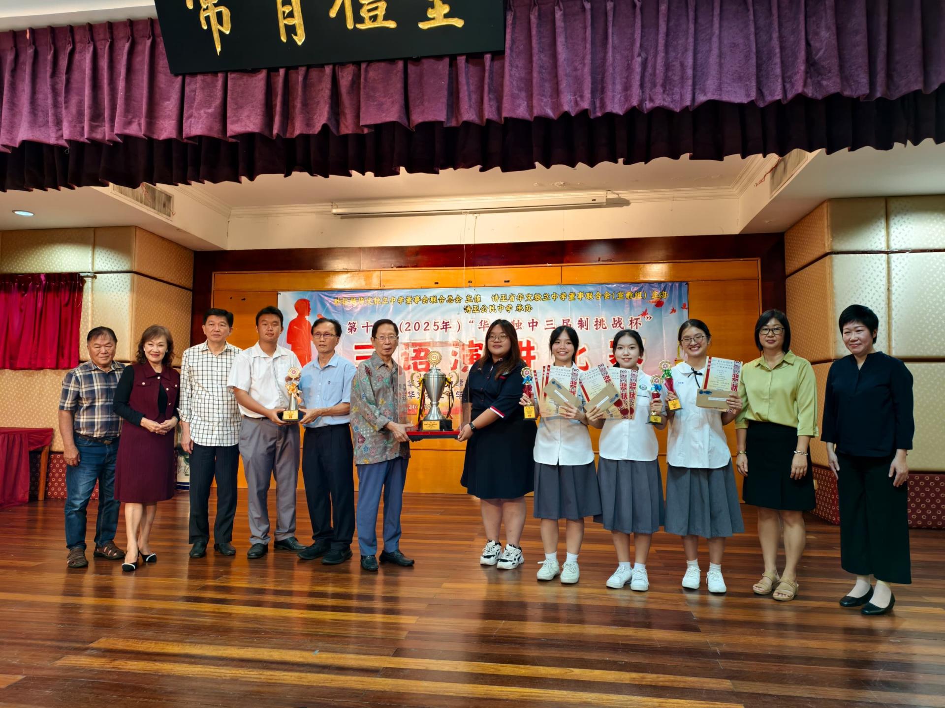 培中生在“砂拉越华文独中三届制挑战杯”三语演讲比赛中夺得总冠军。图为严卉 媚老师（右6）从天猛公拿督刘利民（左6）手中接过挑战杯。
