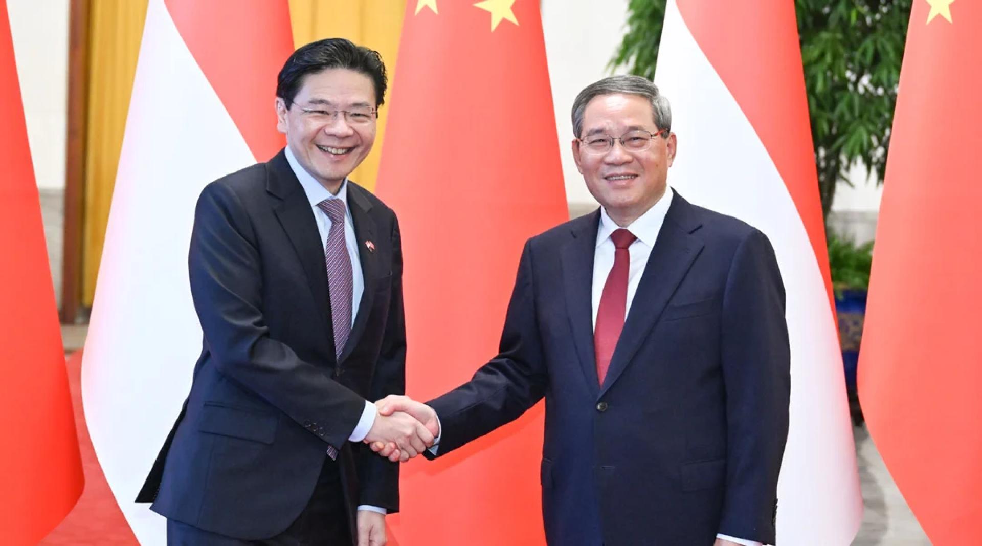 李强（右）23日在北京人民大会堂同来华进行正式访问的黄循财（左）举行会谈。