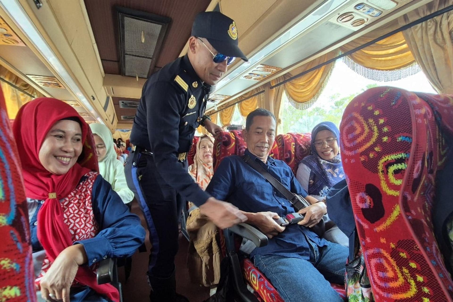 陆路交通局执法人员展开行动，确保巴士司机及乘客系好安全带。（马新社）