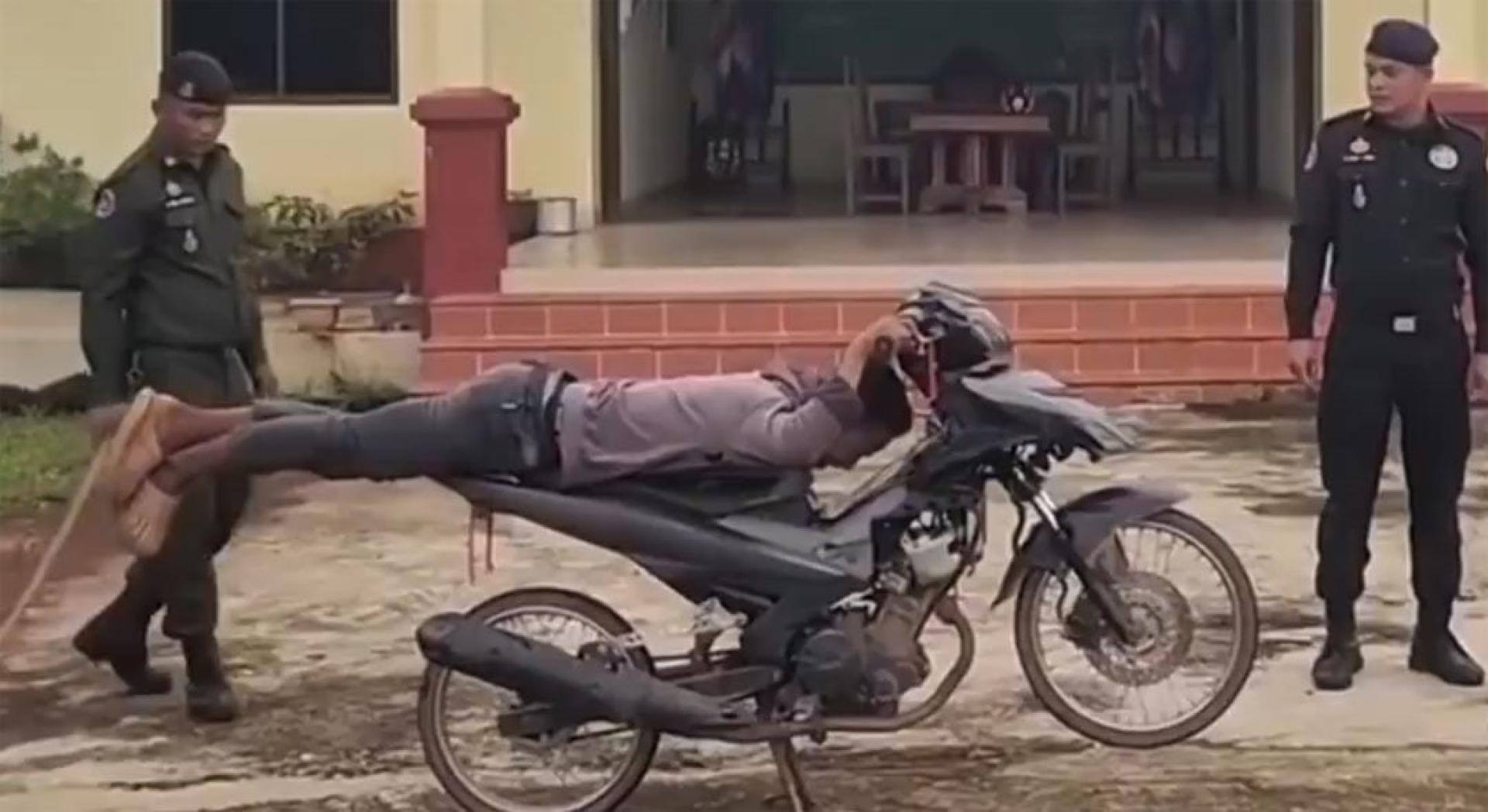 警员命令违规骑士坐在摩托上摆出“超人式飞行”姿势。（视频截图）