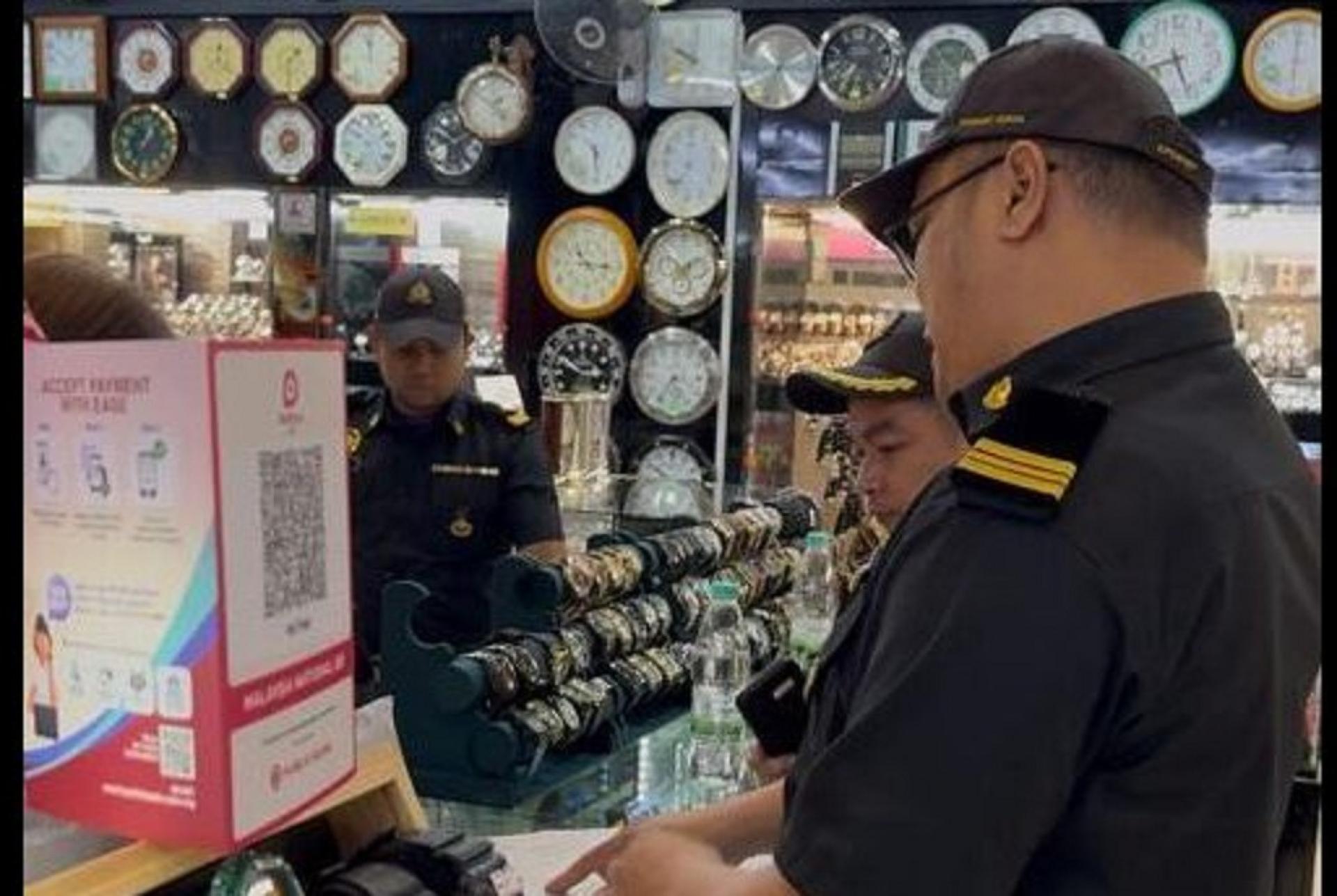 执法人员检查店铺所售卖的手表真伪。