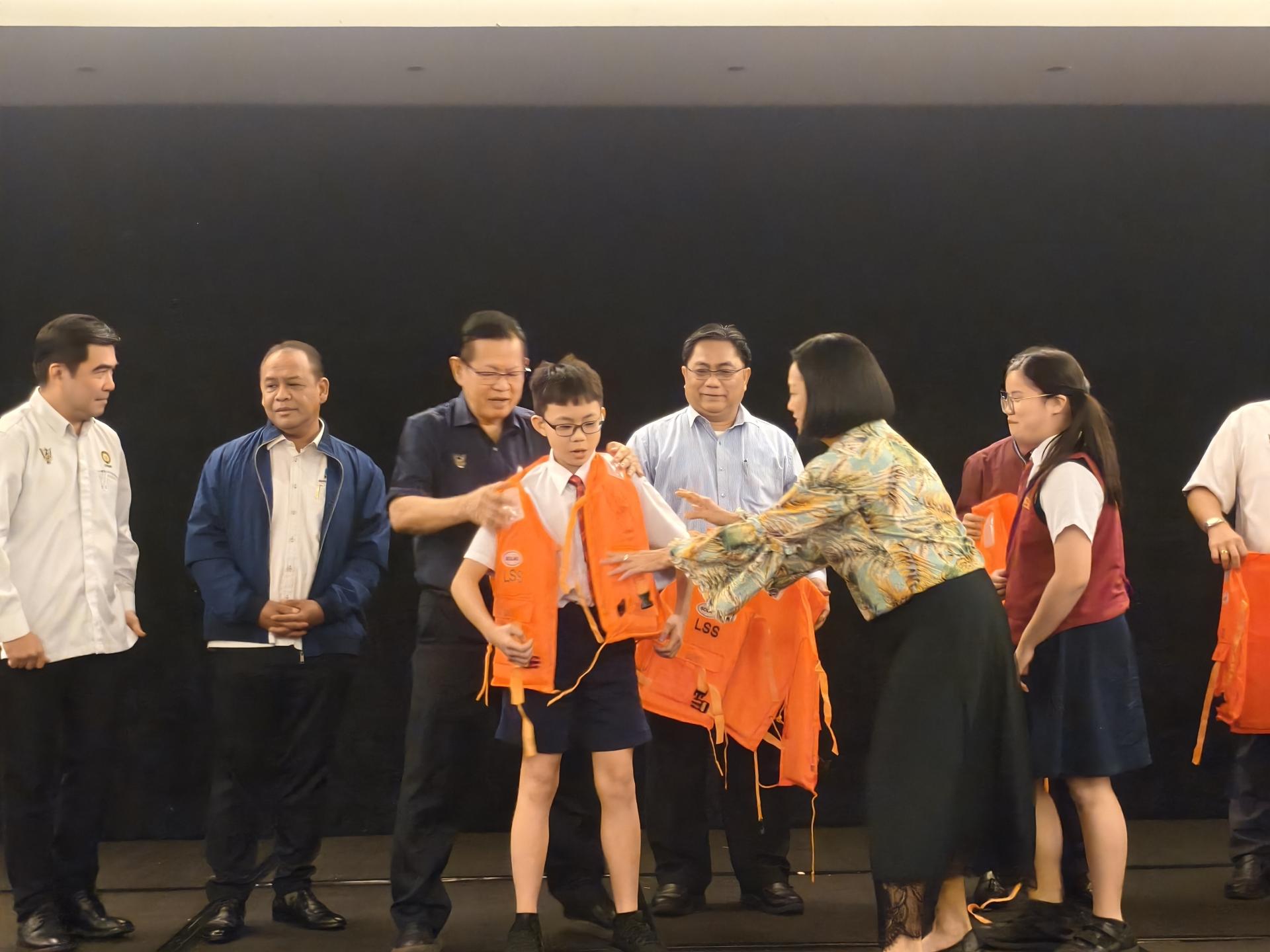 拿督斯里李景胜在美里河流安全宣传运动上派发救生衣给靠沿河地区学校的学生。