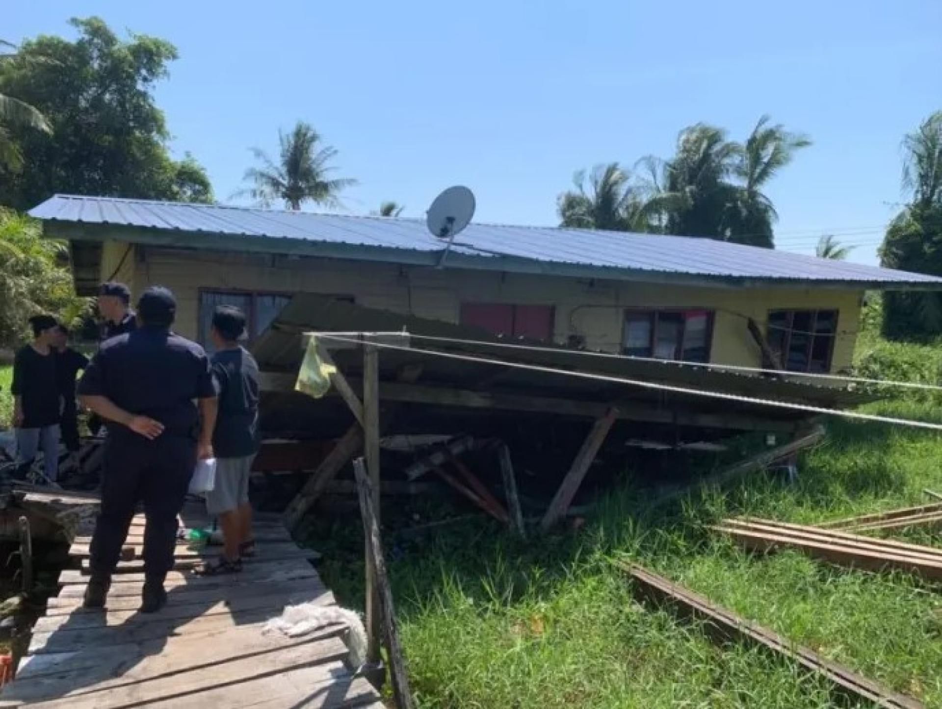 Police officers inspecting the collapsed wooden house in Kampung Masjid Kuala Baram, Miri.