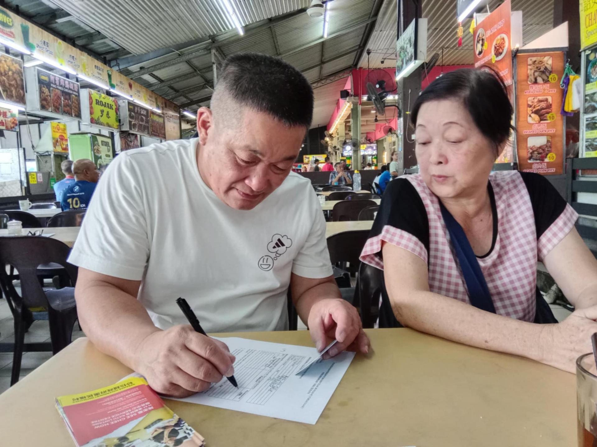 巴都林当区州议员施志豪（左）亲自协助年长者填写“年长者健康福利计划”申请表格。