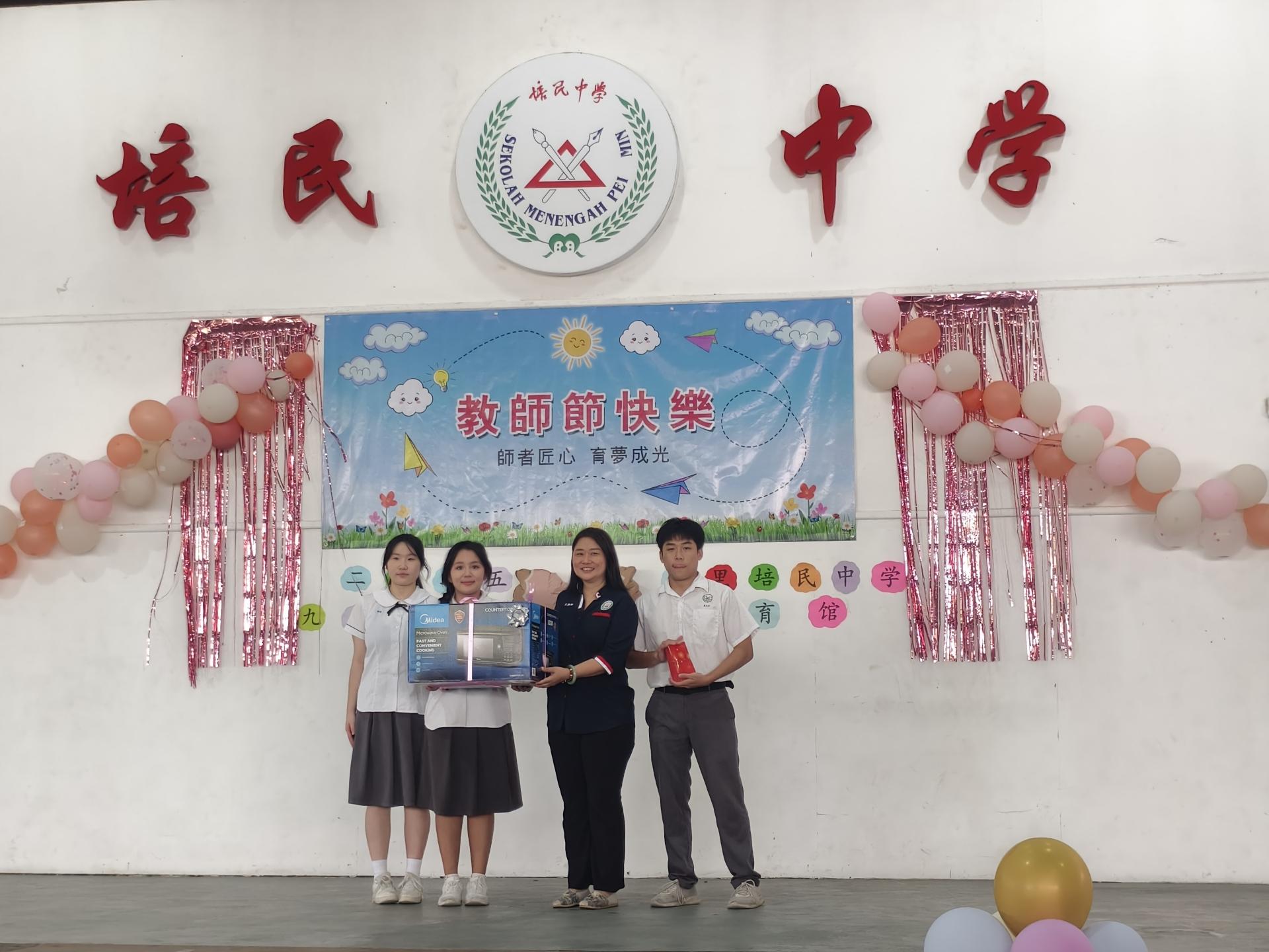 筹备会主席蔡宇涵（左2）赠送教师节礼物给培民中学校长贝美娇。