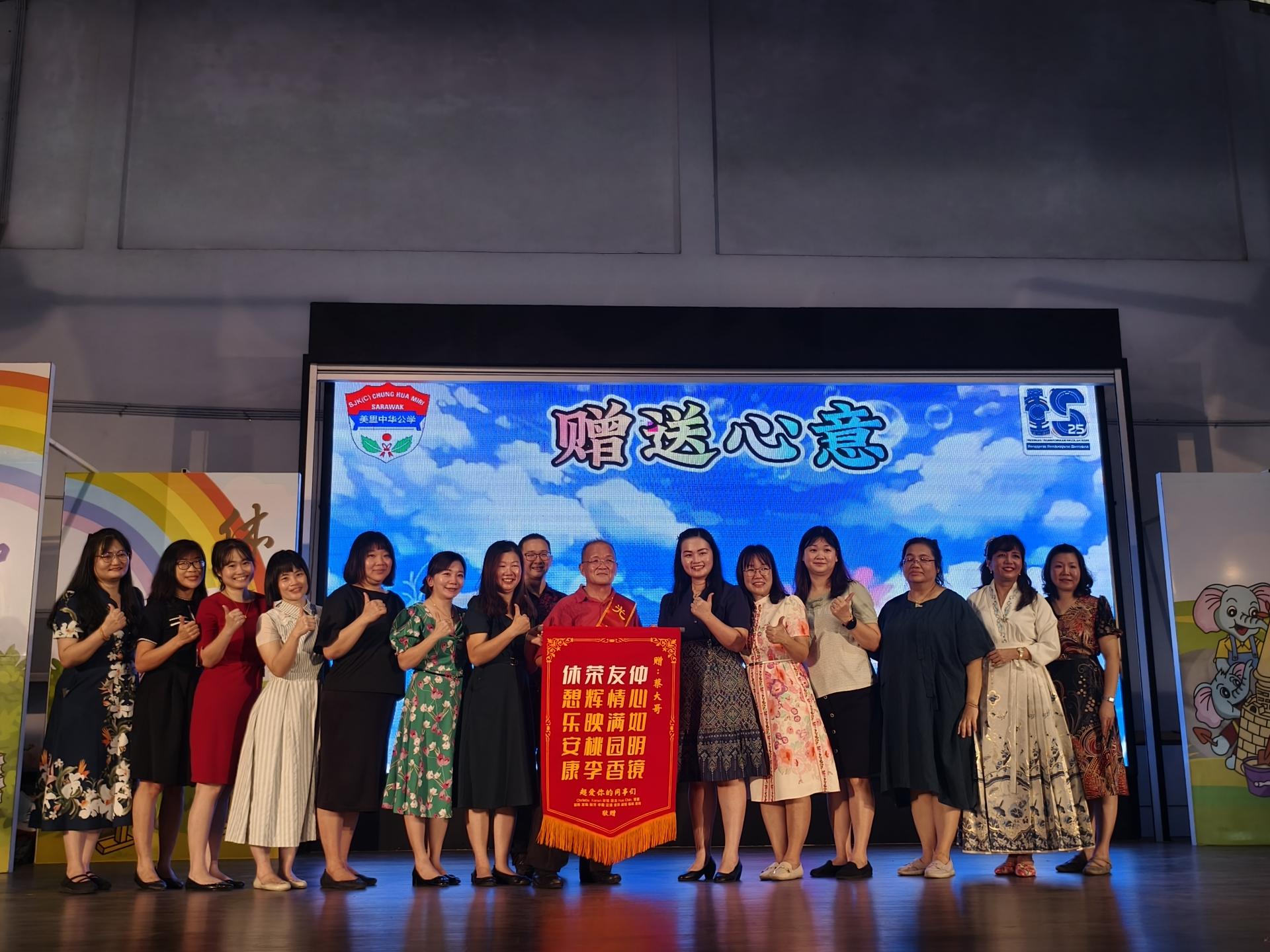 美里中华公学蔡仲友老师（中）在同事们手中接过心意。