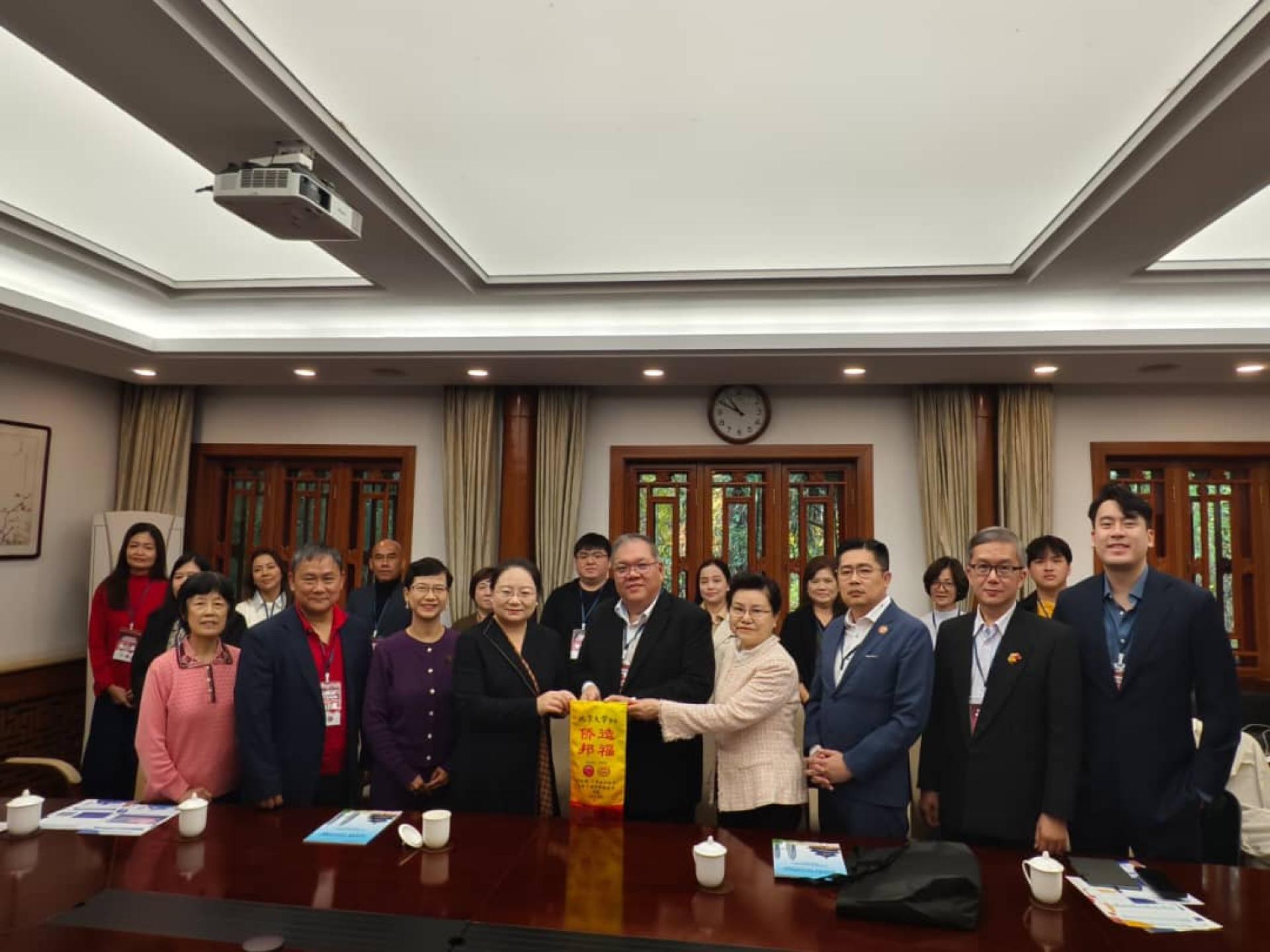 马来西亚砂拉越教育文化代表团团长拿督黄国辉（左5）移交纪念锦旗予北京大学对外汉语教育学院副院长路云（左4）与北京大学医学部侨联副主席、药学院教授黄河清（右4）。古晋中友会教育主任吴泽源（左2）、砂拉越中国友好协会秘书长许瑞益（右3）、古晋中华总商会青商团团长黄福庆（右2）。