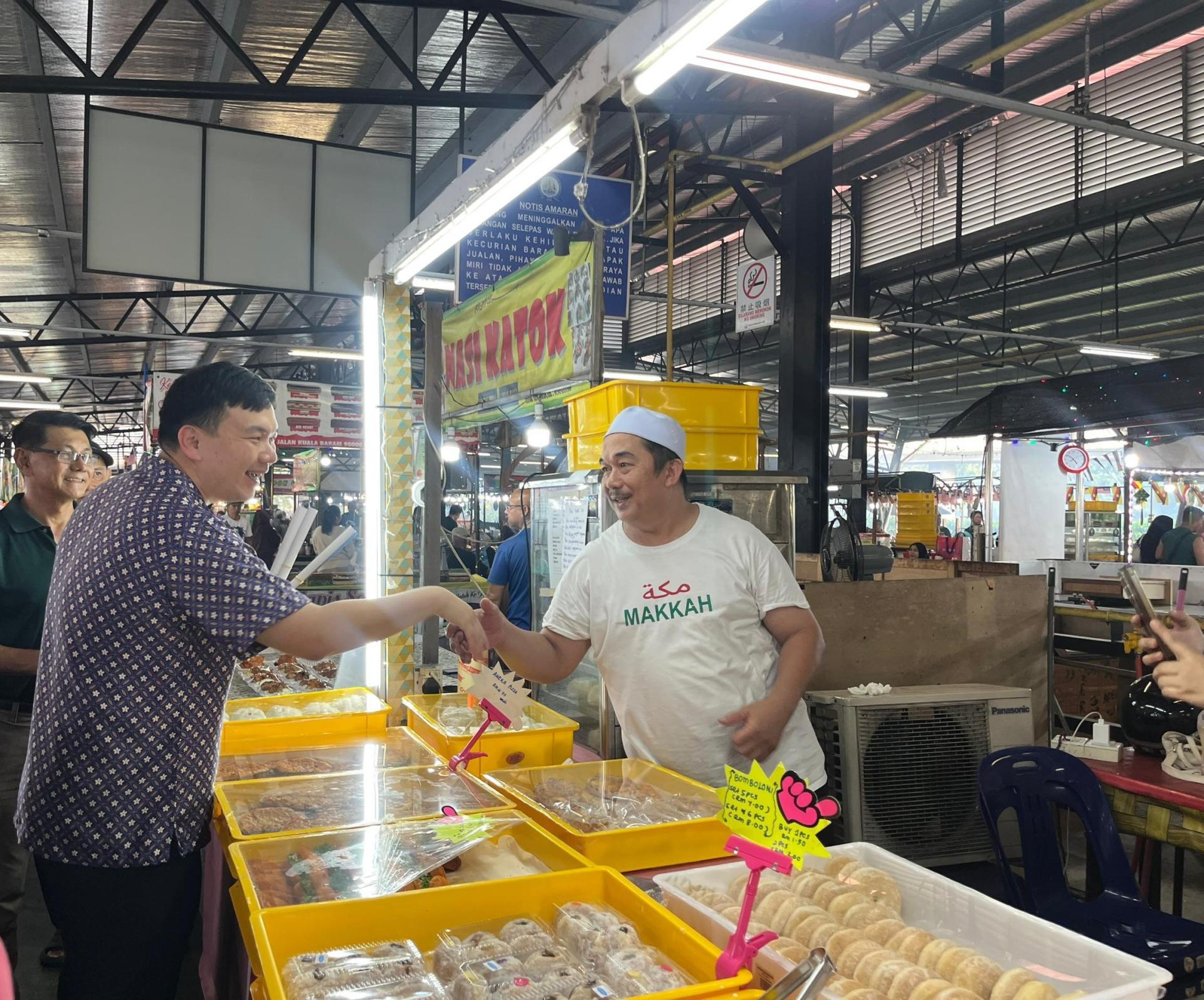 美里国会议员赵俊文（左）与青统夜市业者握手交流。