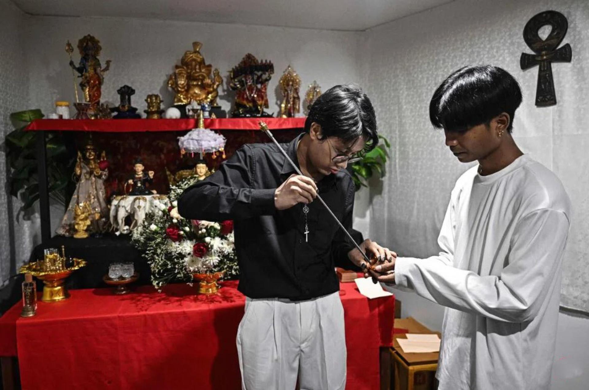 旅居泰国曼谷的缅甸占卜师林尼奥达亚（左）给信徒施法文身。缅甸2021年发生政变后，林尼奥达亚曾向军政府领导人敏昂莱施法，结果被判入狱。