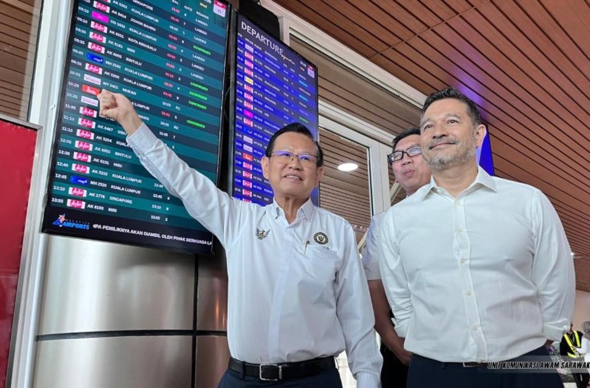 拿督斯里李景胜（左）指着婆罗洲航空的航班标志。
