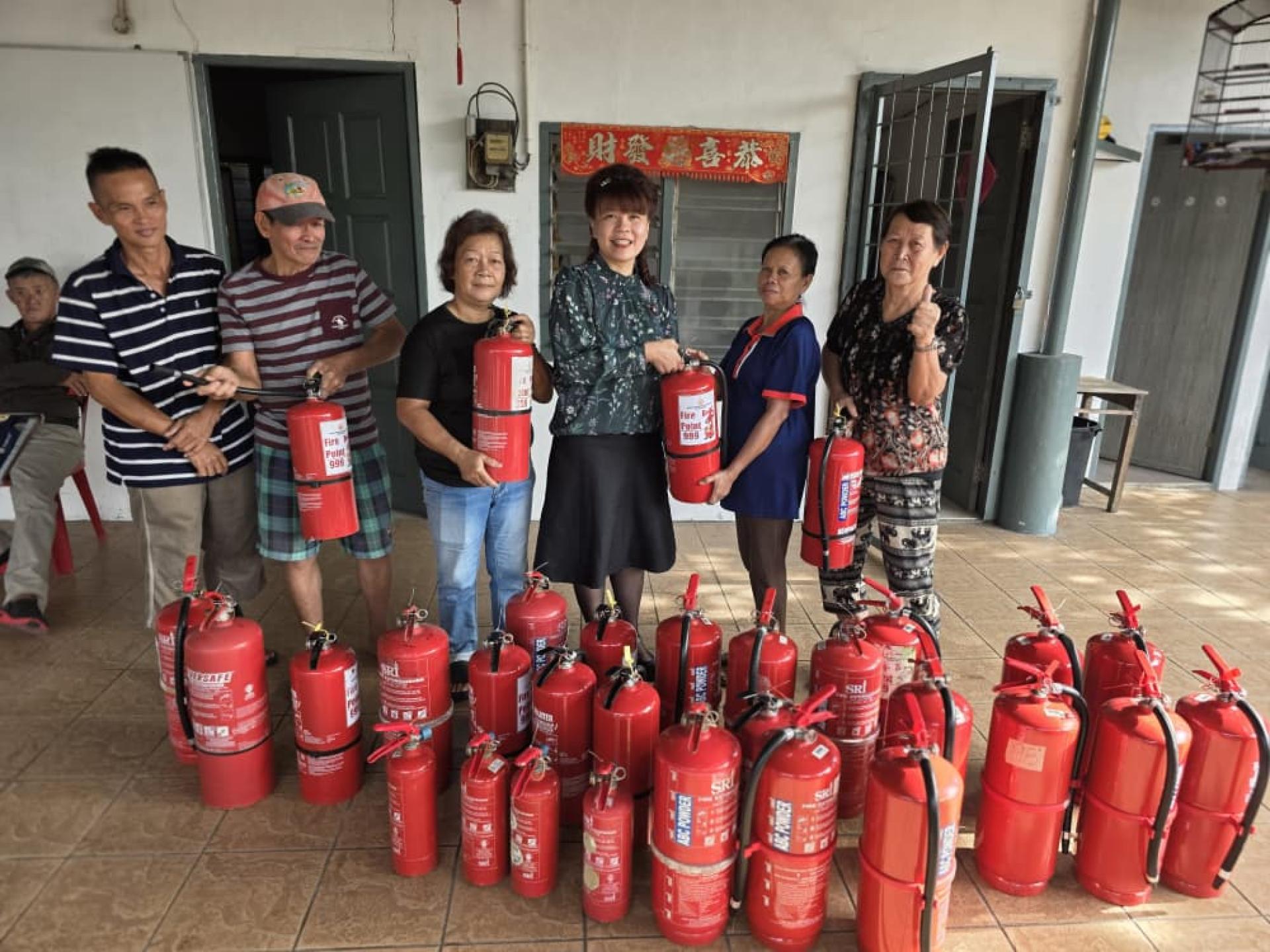 民主行动党朋岭区州议员杨薇讳（右3）移交灭火器给其中一名居民。