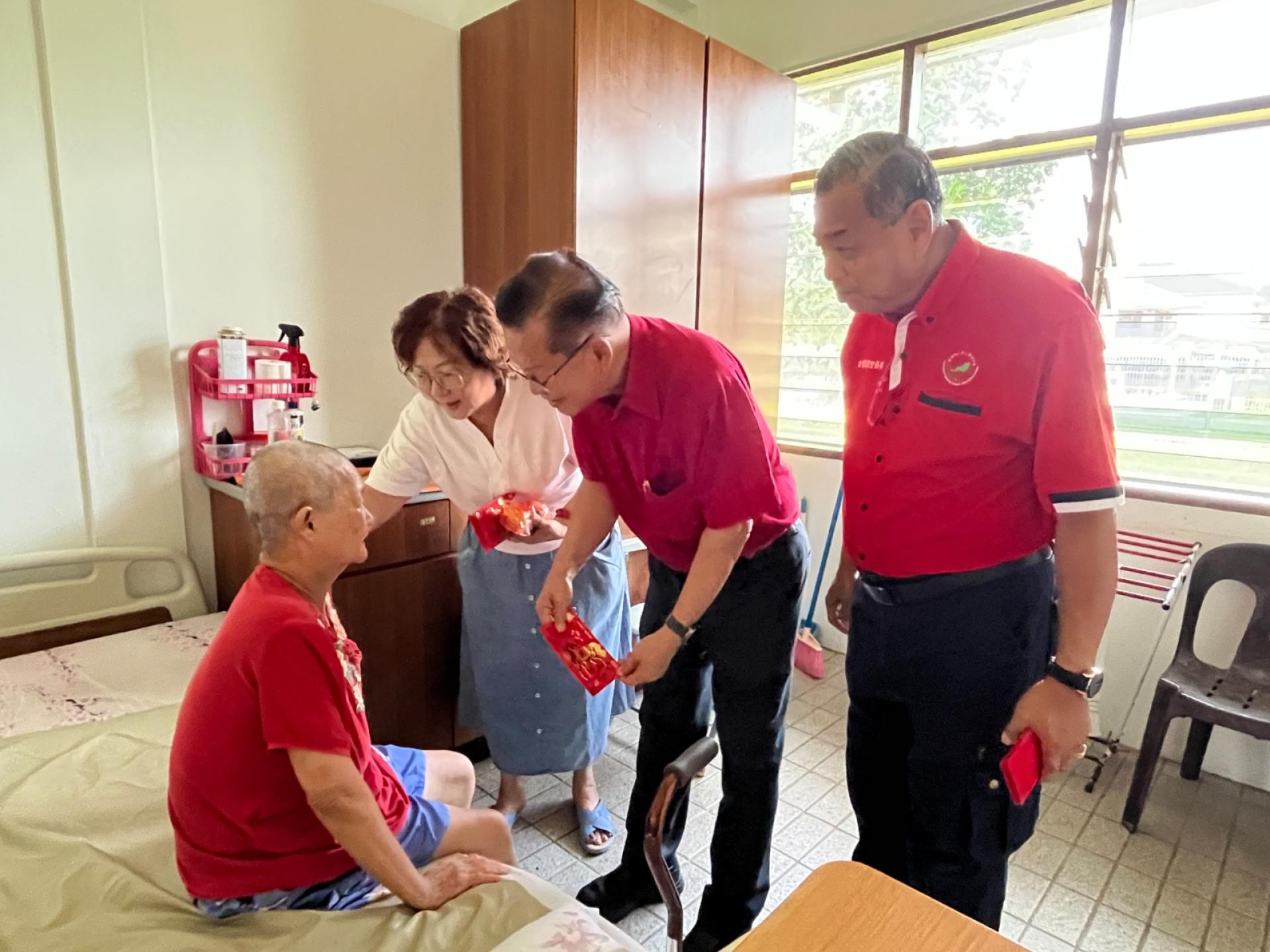 砂拉越广东乡团联合会永久名誉顾问拿督斯里李景胜（中）在美里老人之家主任本固鲁方凤金（左）率领，与会长拿督斯里甘保祥（右）派发新春红包的年长者。