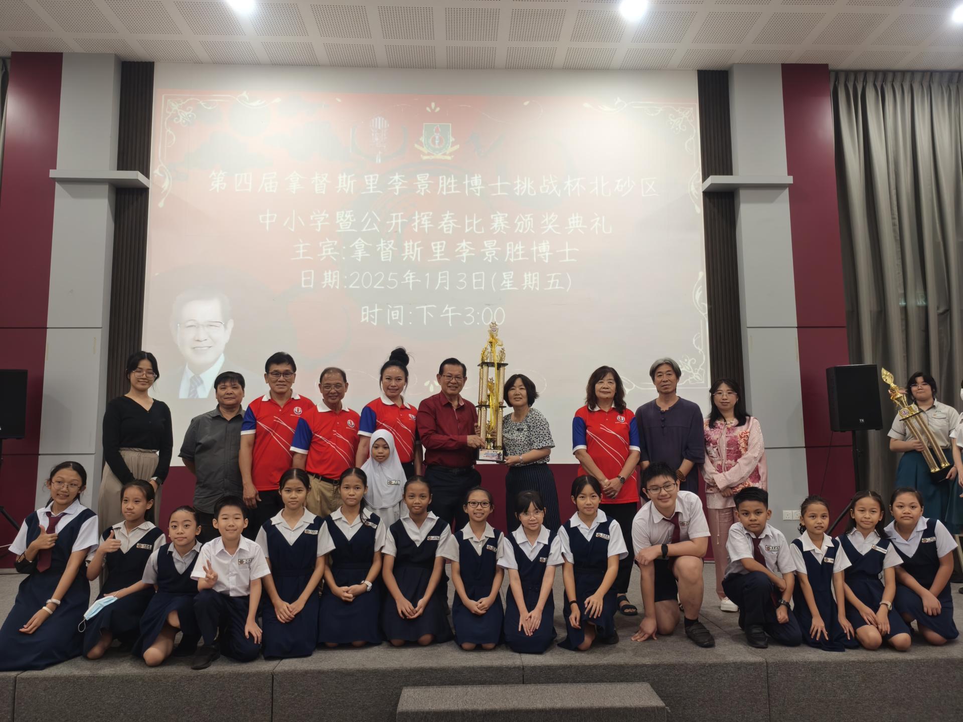 主宾拿督斯里李景胜（左者）颁发小学组挑战杯予三连冠的美里埔奕中华公学，由副校长甘美  美接过。