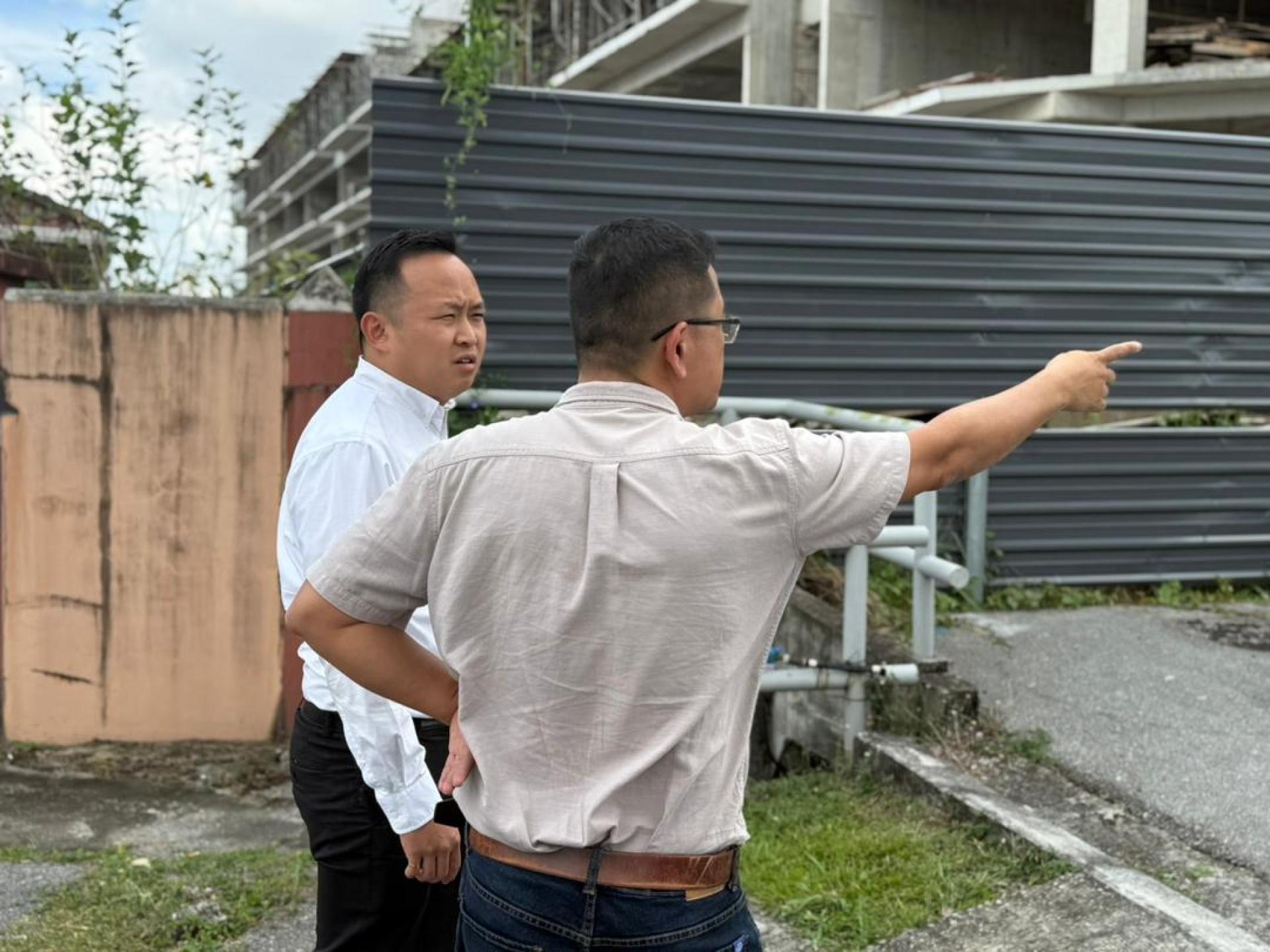 江峰年（左）在现场向相关人士了解情况。