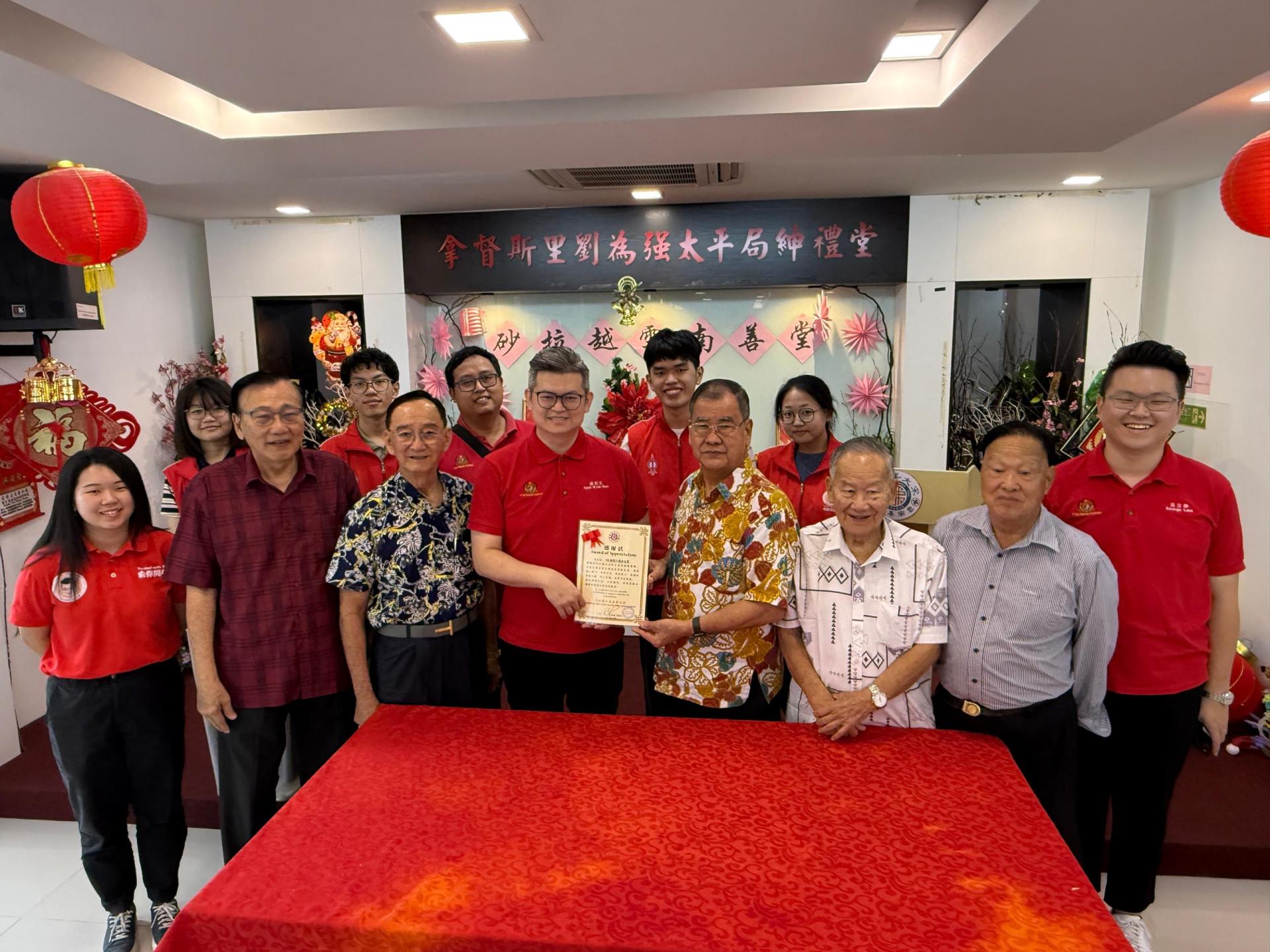 砂拉越云南善堂主席郑文新（右4）赠送感谢状予古晋市国会议员俞利文（左4）。前排左起俞利文特别助理张嫣宁、砂拉越云南善堂副国英文书郑文发、副主席郭兴开、副主席钟名宝、副主席郑瑞福、及俞利文特别助理蓝立康。