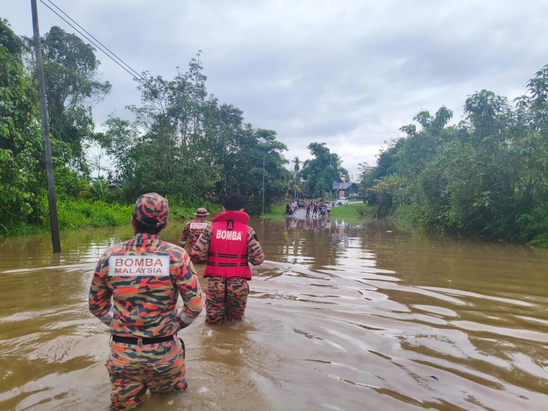 Firefighters wade through the floodwaters.