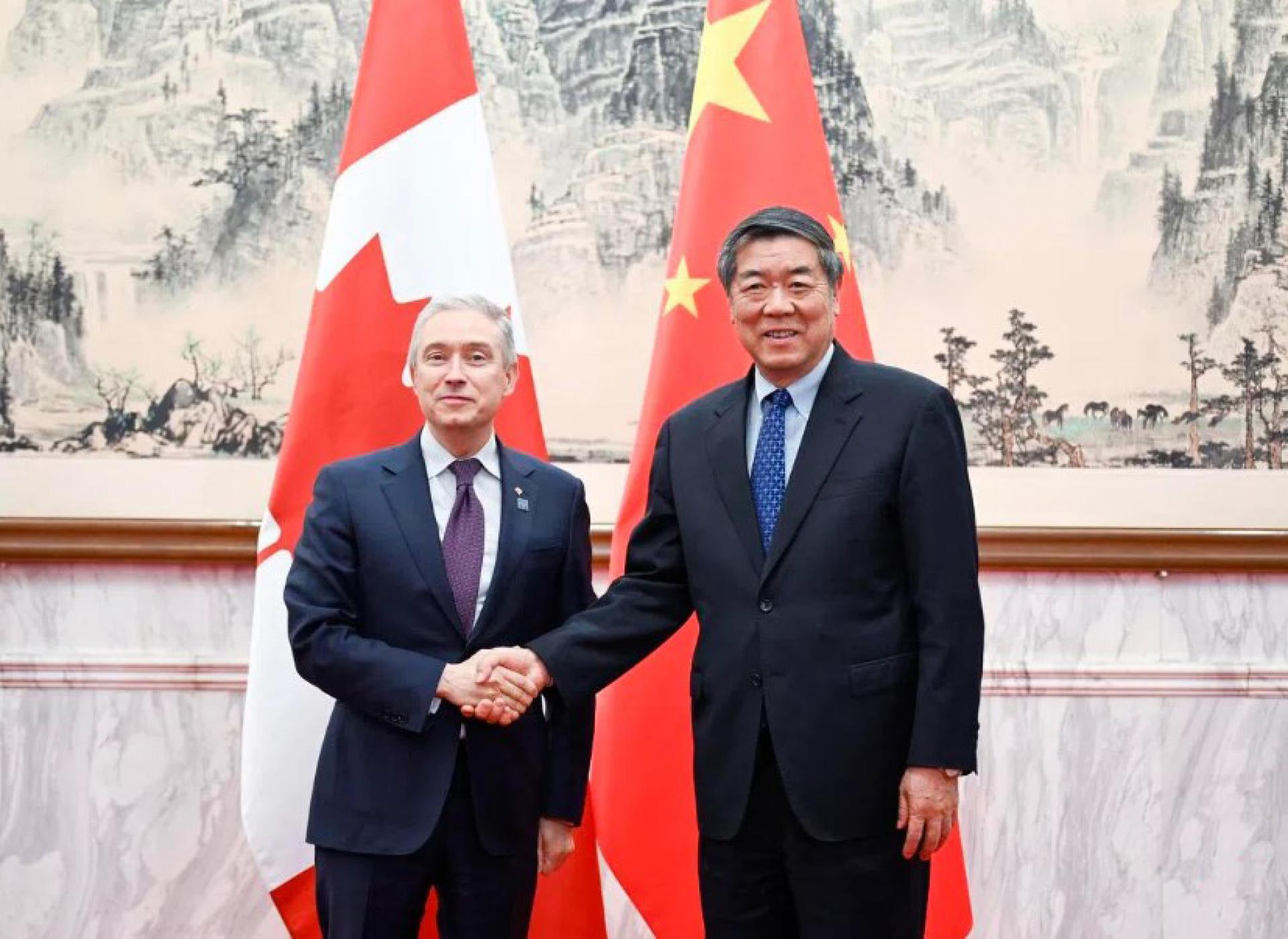 中国副总理何立峰（左）星期五（4月3日）在北京与加拿大财政部长商鹏飞会面握手。