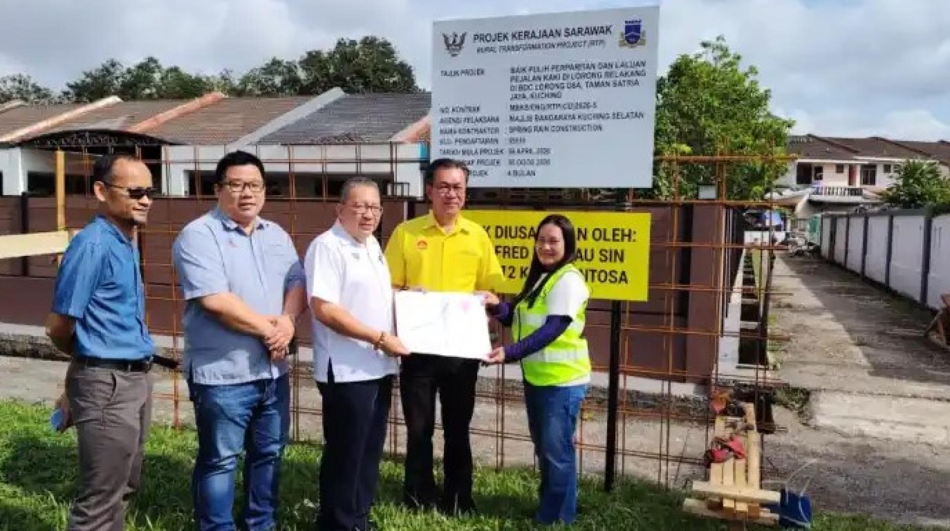 黄鸿圣（中）于2026年4月20日向Spring Rain Construction代表移交委任状，负责BDC Lorong D8A（Taman Satria Jay）后巷排水系统及人行道提升工程，哥打圣淘沙州议员叶耀星（右2）亦在场见证。